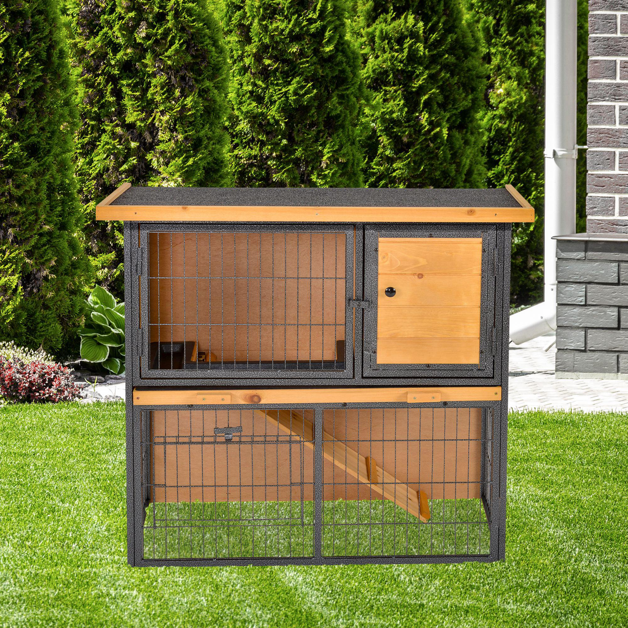 Ein hölzerner Kaninchenstall mit Gittern und Dach, auf Rasen platziert, mit grünen Büschen im Hintergrund.