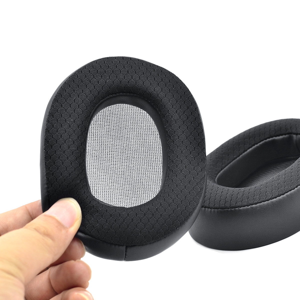 Due cuscinetti auricolari neri per cuffie. Uno è tenuto da una mano. Sfondo bianco.