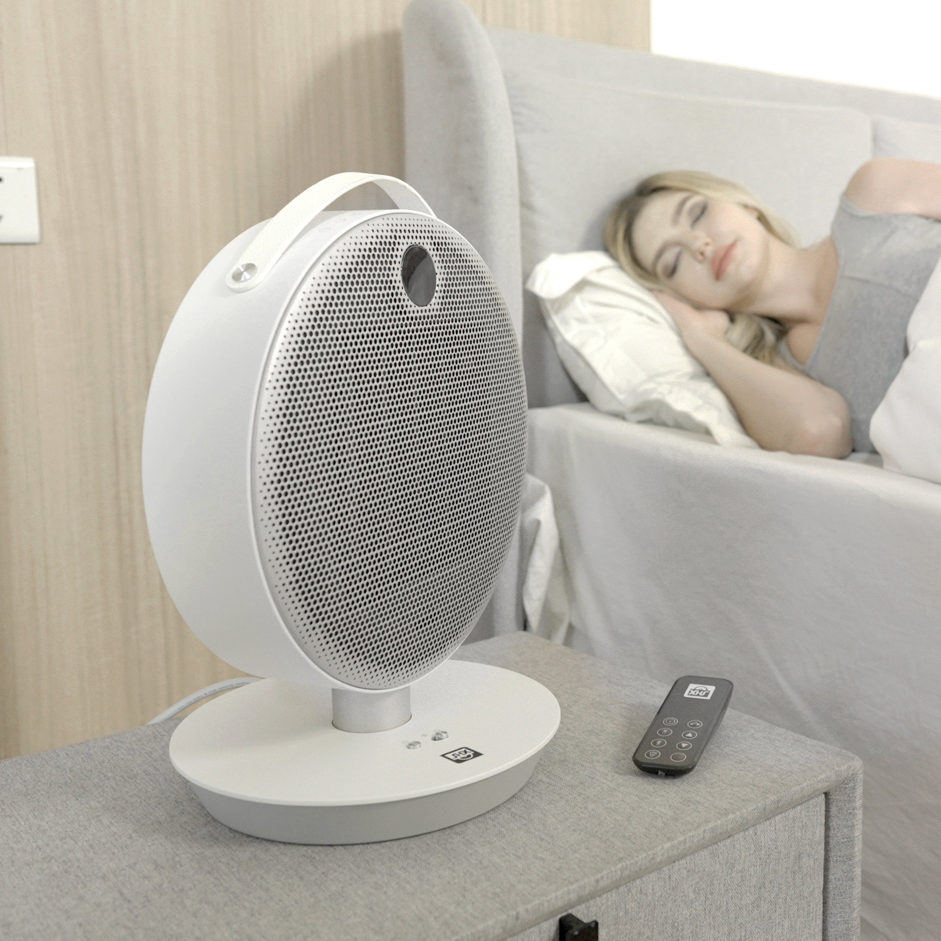Ein weißer Luftreiniger neben einer schlafenden Frau in einem Bett.
