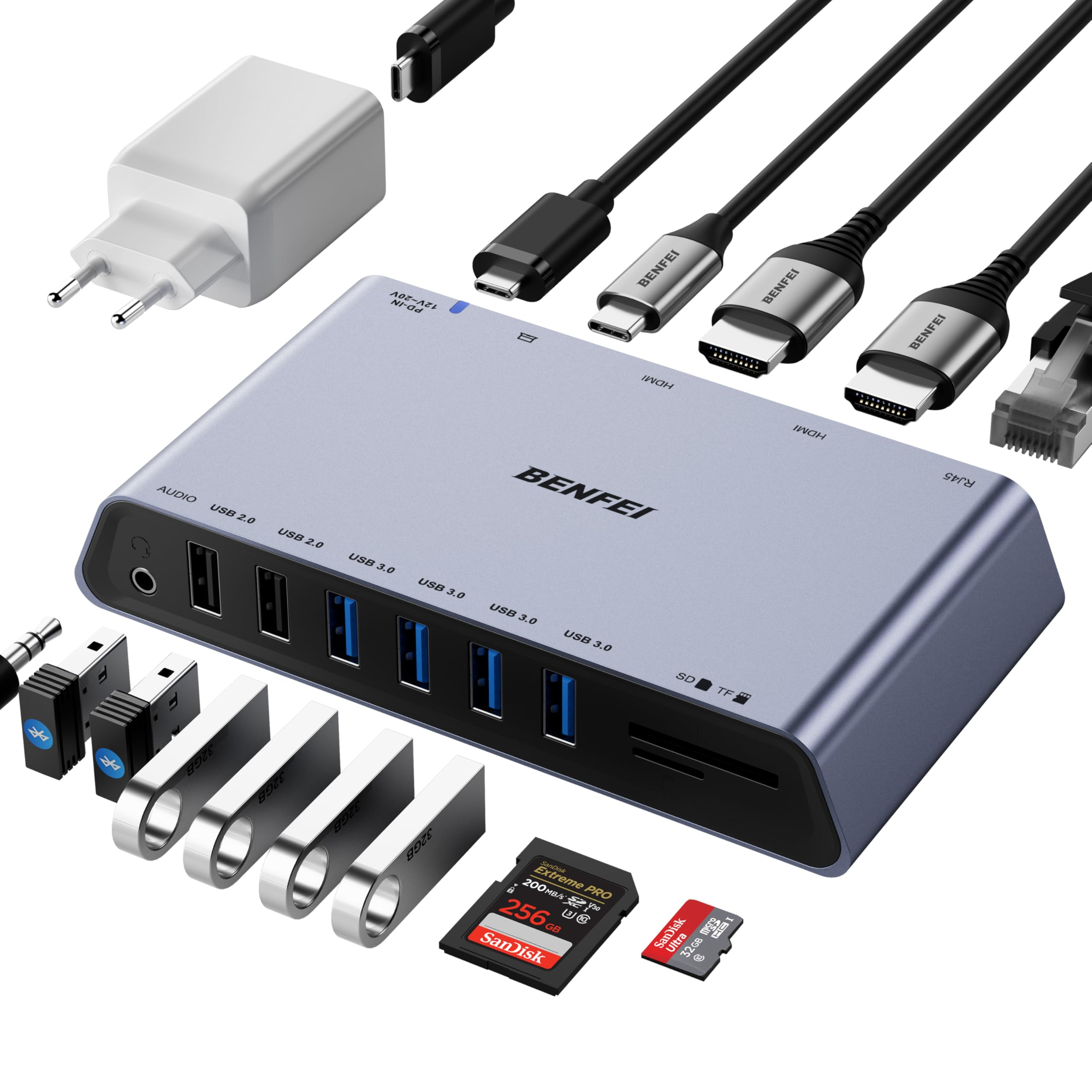 Ein silberner Hub mit mehreren Anschlüssen, Kabeln und USB-Laufwerken befindet sich auf einer weißen Oberfläche. Ein Ladegerät und SD-Karten sind ebenfalls vorhanden.