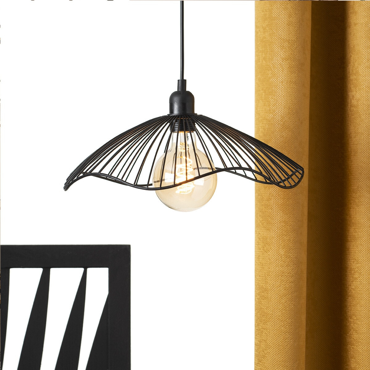 Black wireframe lamp with lit bulb, next to yellow curtain and black chair.