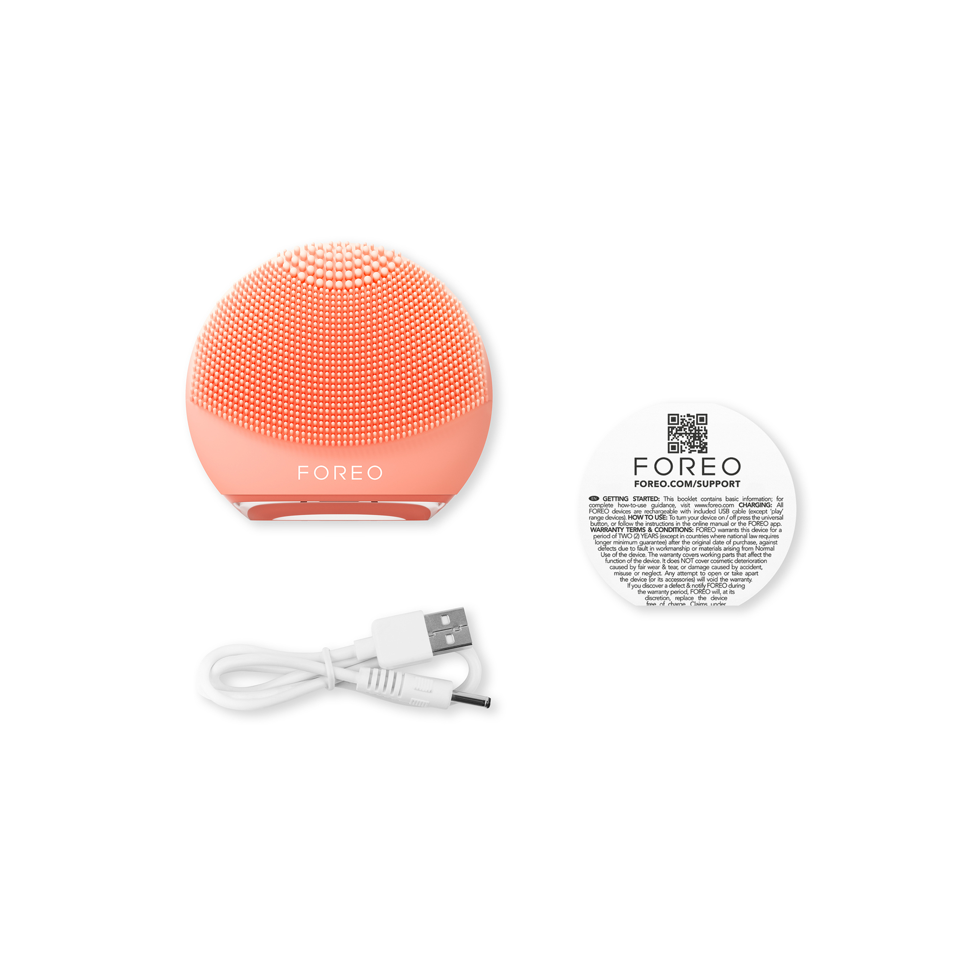 Peach-colored FOREO face brush, white cord, and small white document with text and QR codes.