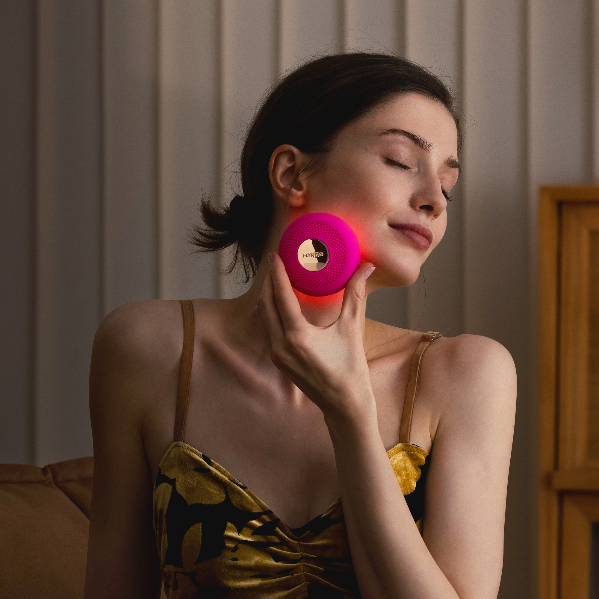 Woman using a pink Foreo device on her face, with red light.