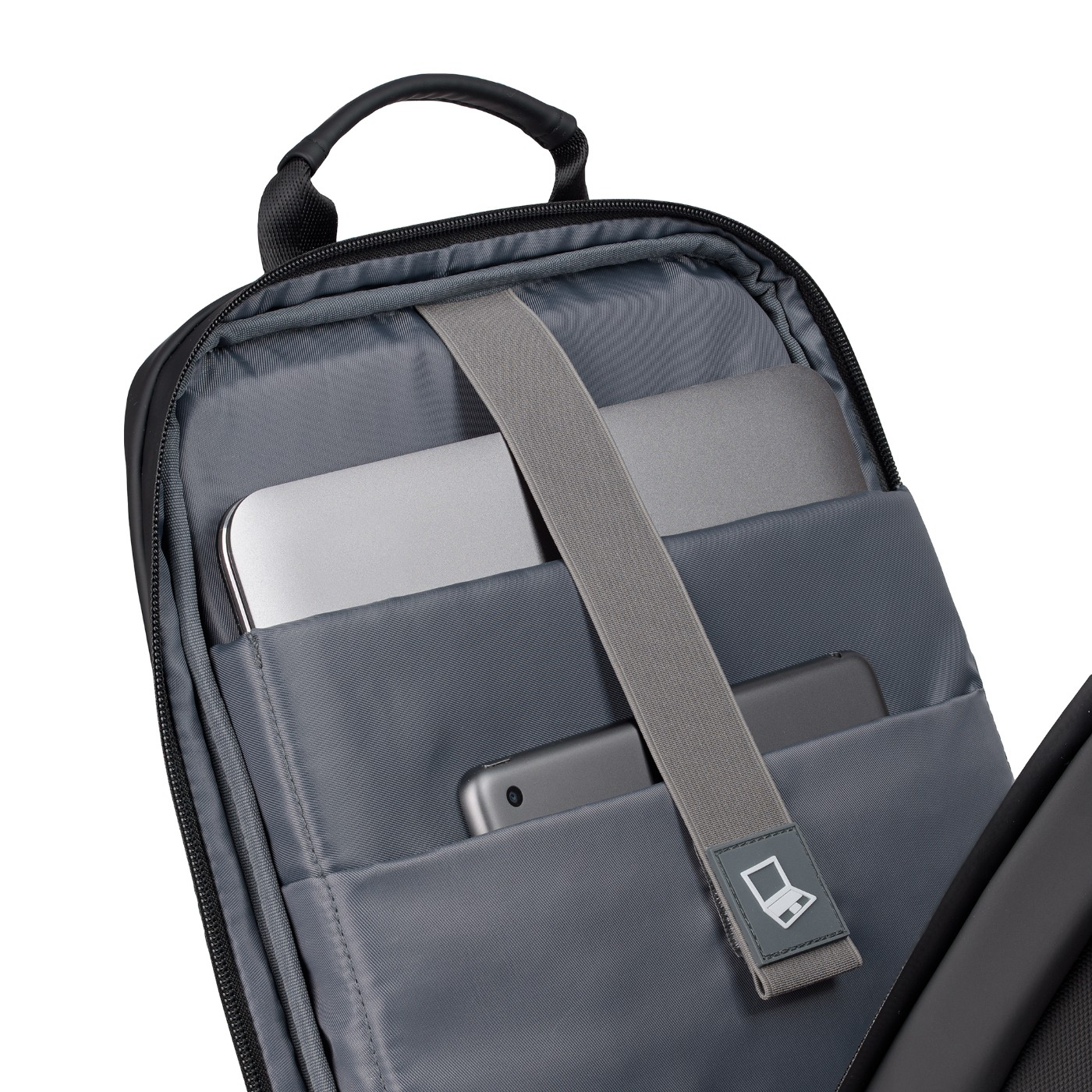 Otwarta czarna komora plecaka. Zawiera szare kieszenie na laptopa i telefon oraz szary pasek.