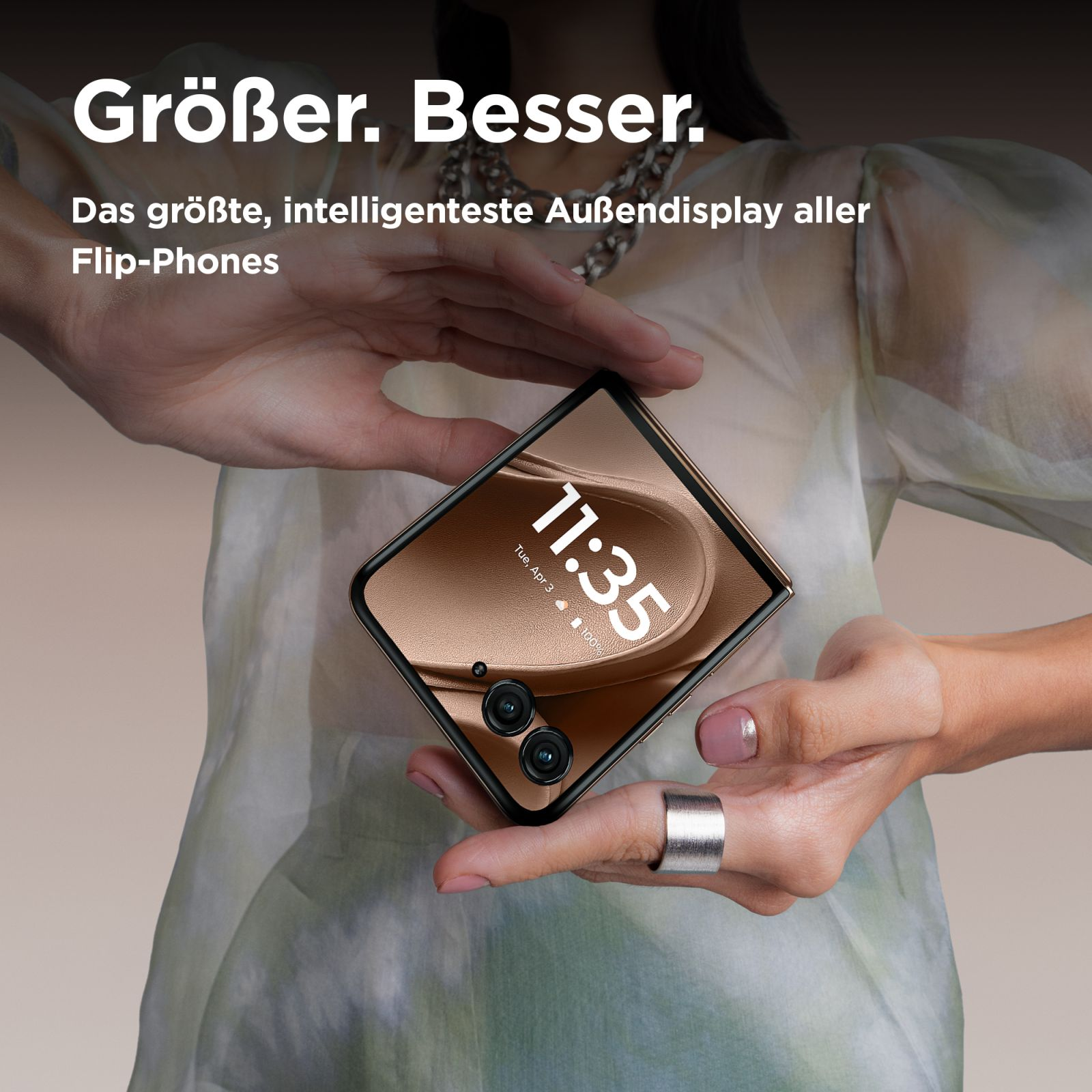Eine Person hält ein geschlossenes Klapphandy, das den äußeren Bildschirm mit der Uhrzeit zeigt.