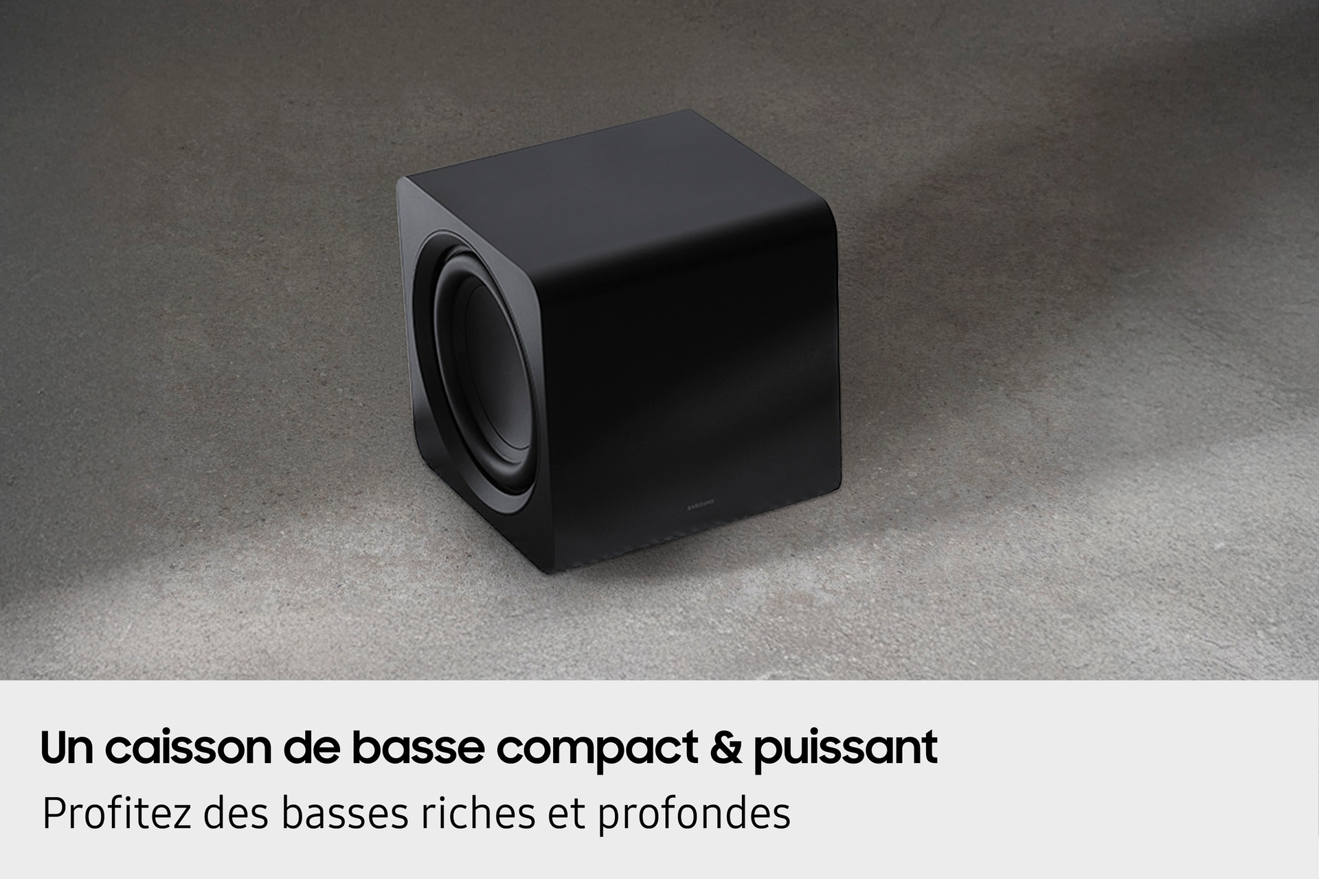 Ein schwarzer Subwoofer auf einer grauen Oberfläche mit Text über kraftvollen Bass.