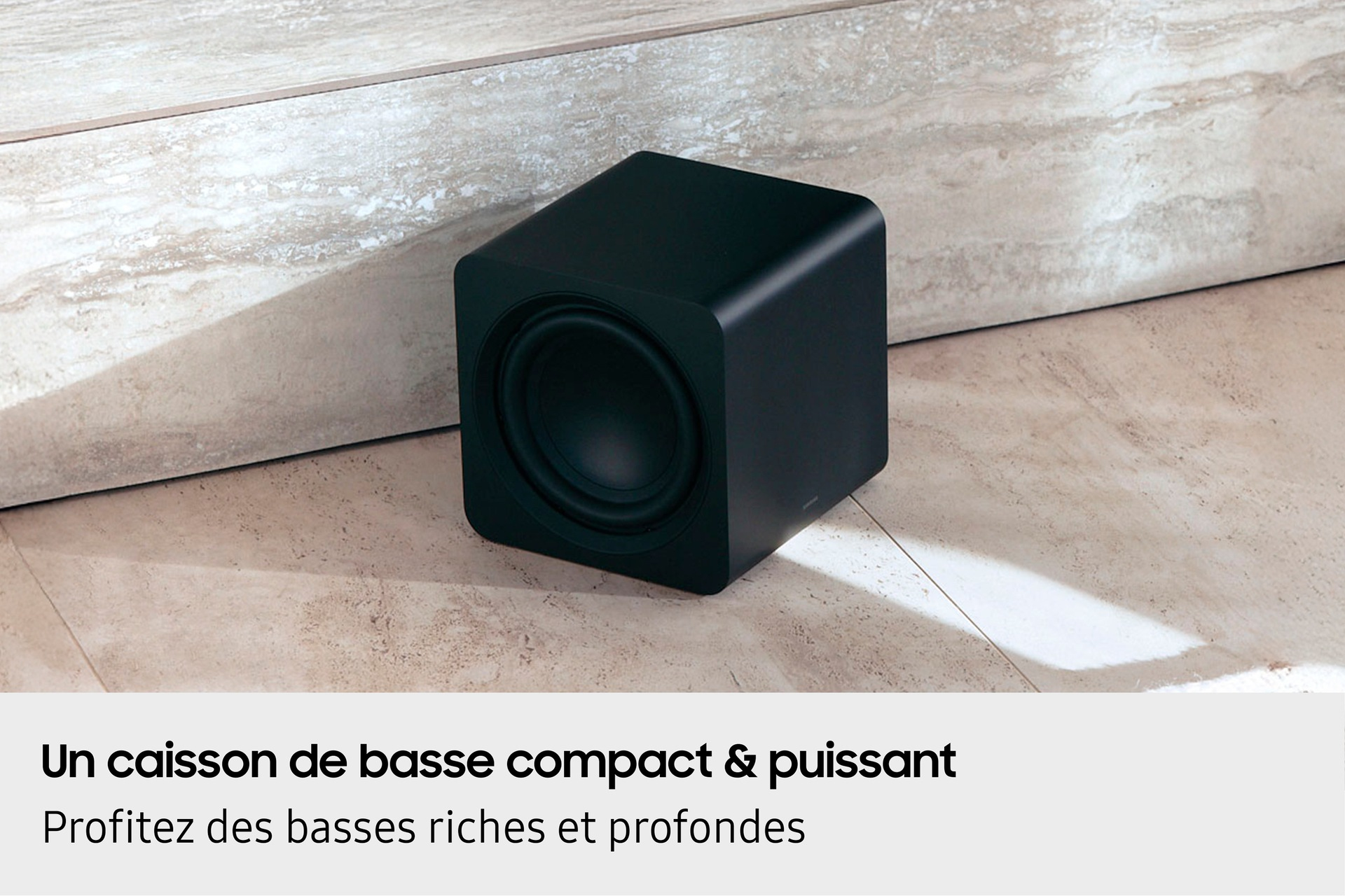 Czarny subwoofer na podłodze z płytek, zbliżenie.