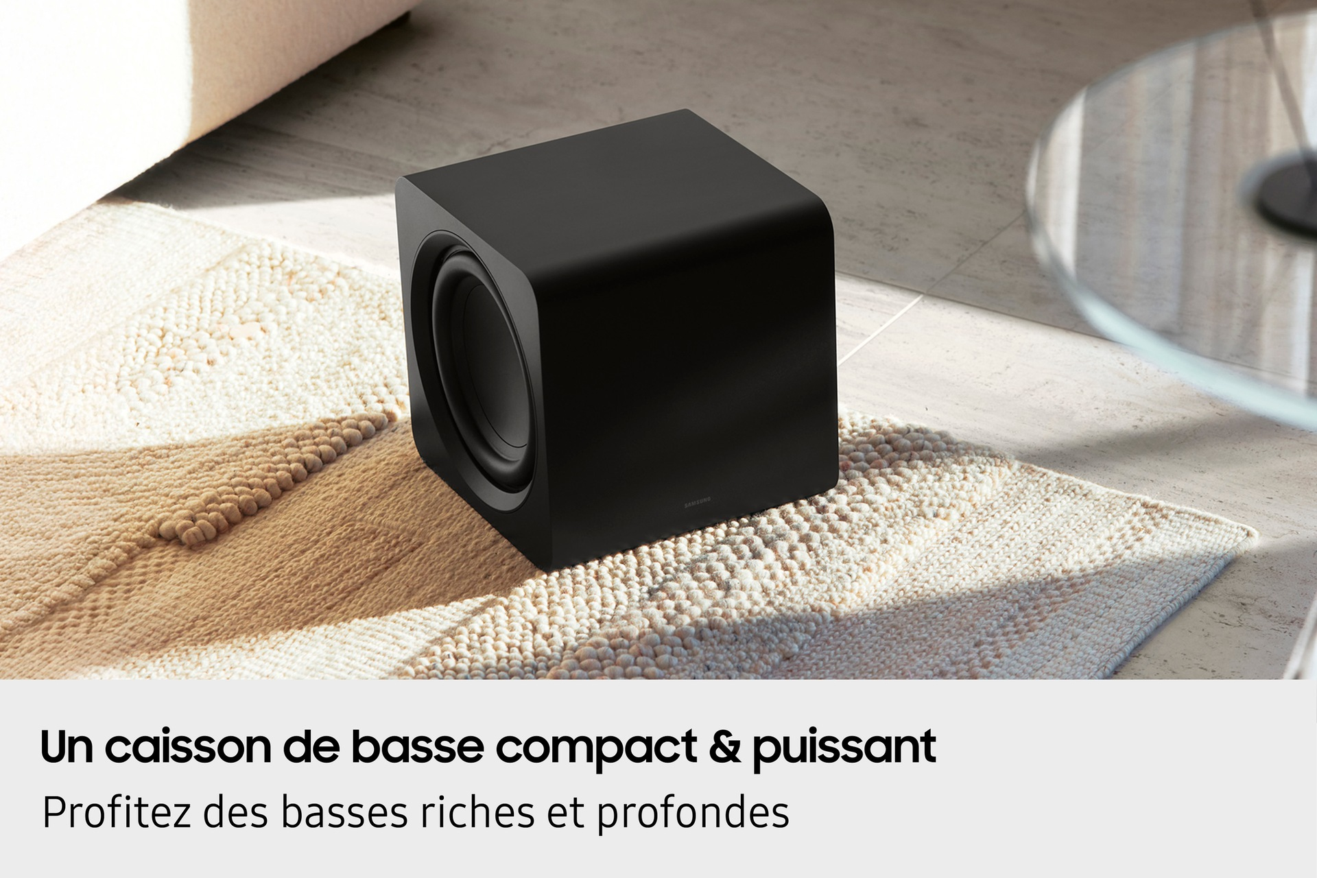 Czarny subwoofer w salonie, na wzorzystym dywanie.