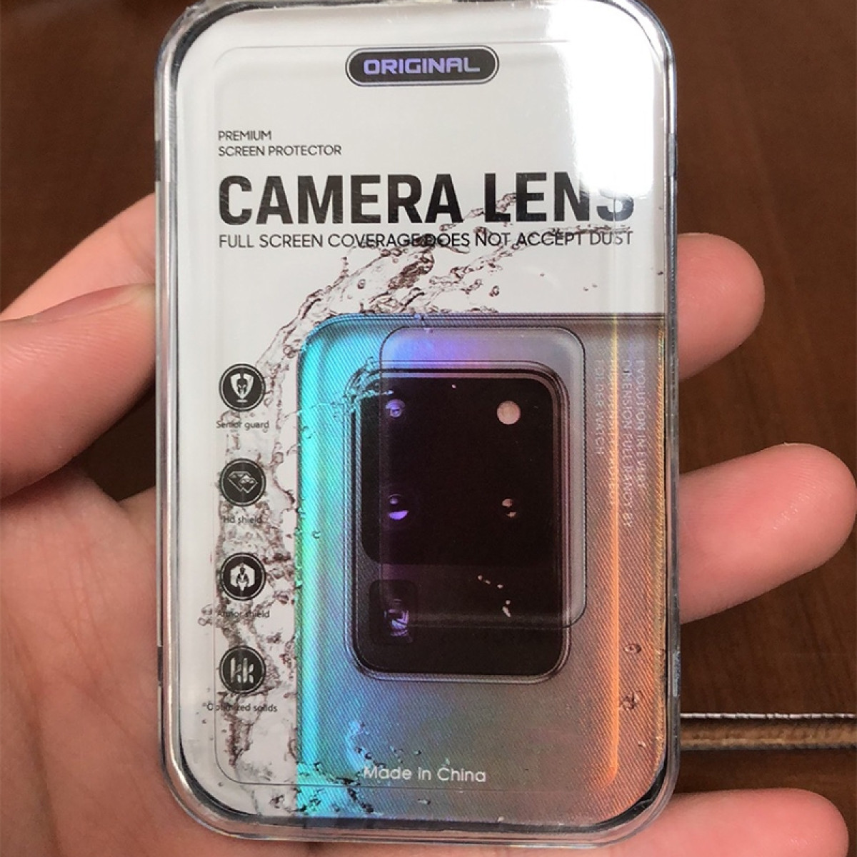 Una confezione per una protezione per lenti della fotocamera tenuta in mano.