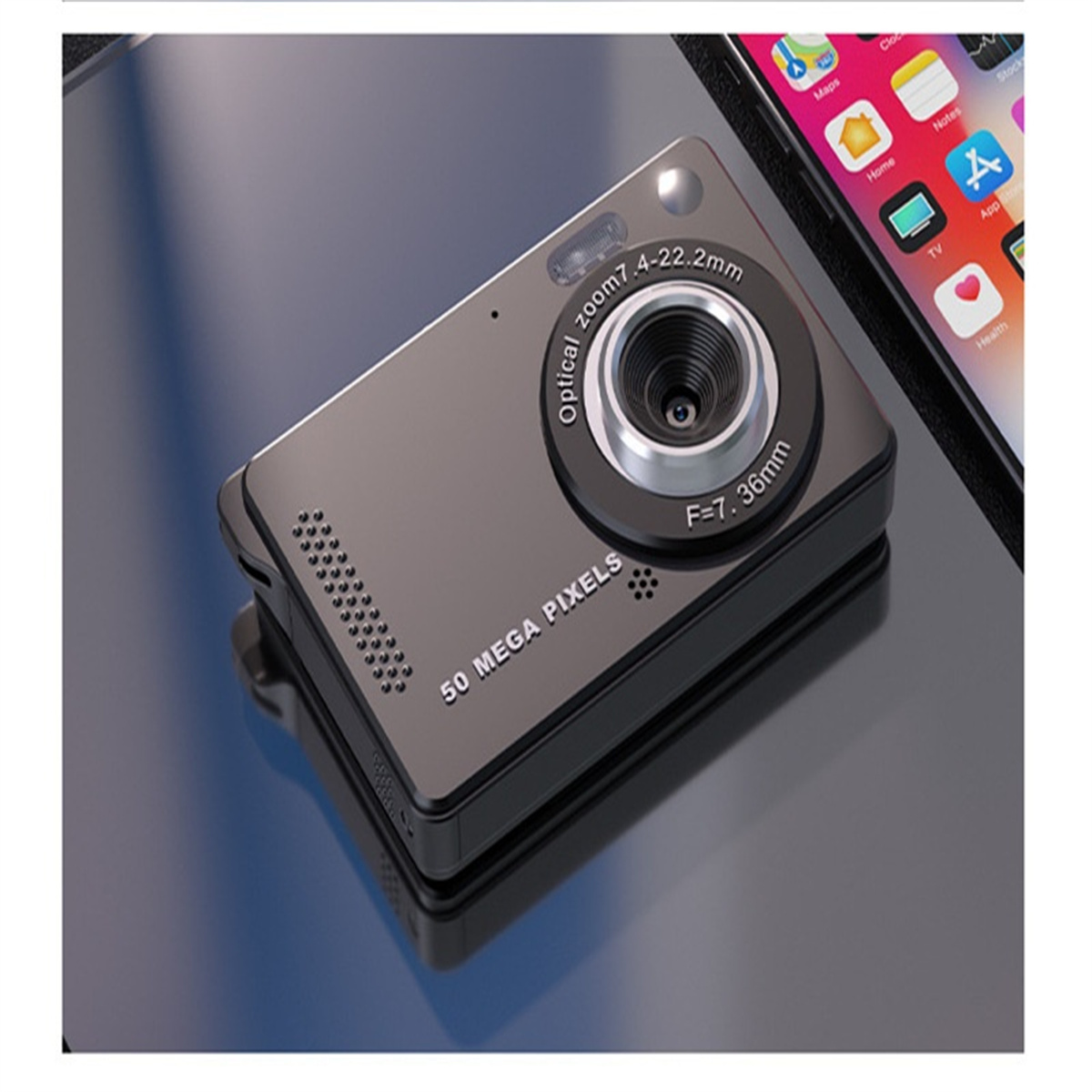 Schwarze Kompaktkamera mit 50 Megapixeln. Sie befindet sich auf einer reflektierenden Oberfläche. Ein Telefon ist im Hintergrund.