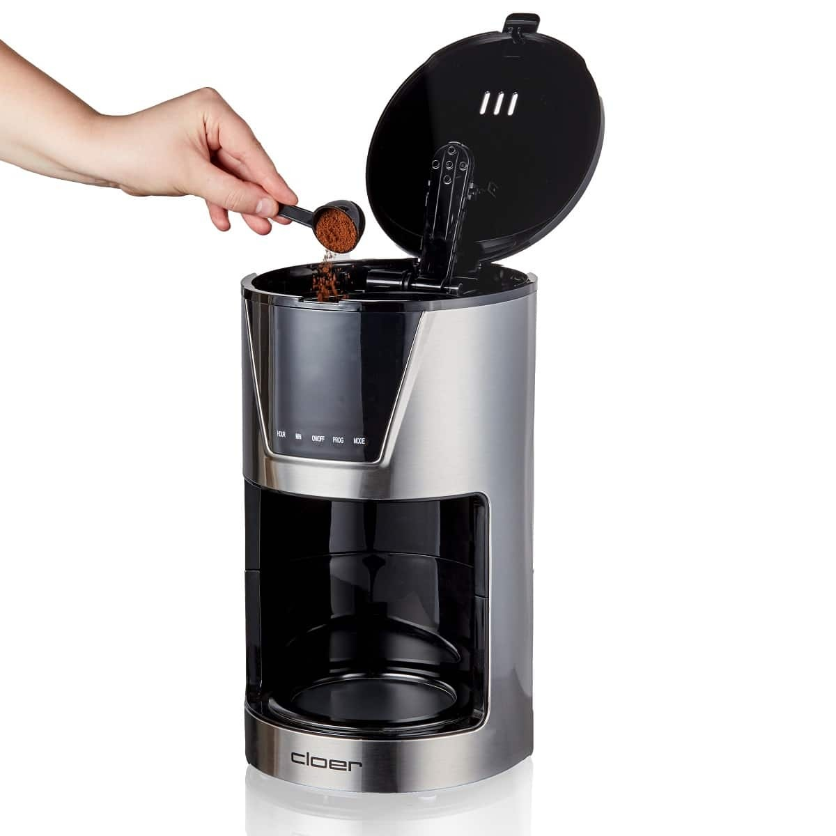 Ręka wsypuje zmieloną kawę do ekspresu do kawy ze stali nierdzewnej z otwartą pokrywą.