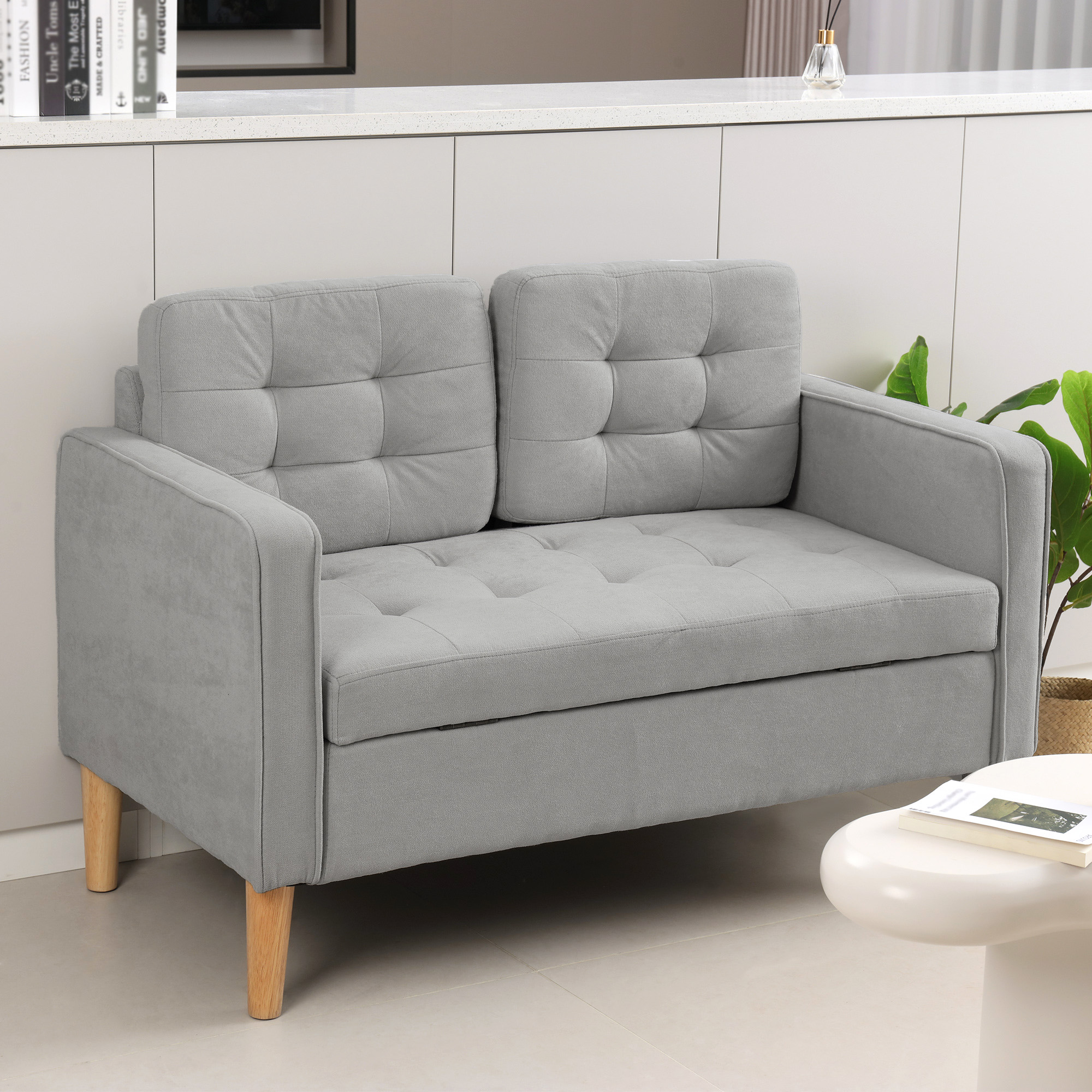 Graues Sofa mit Knopfheftung, hellen Holzbeinen, weißem Hintergrund.
