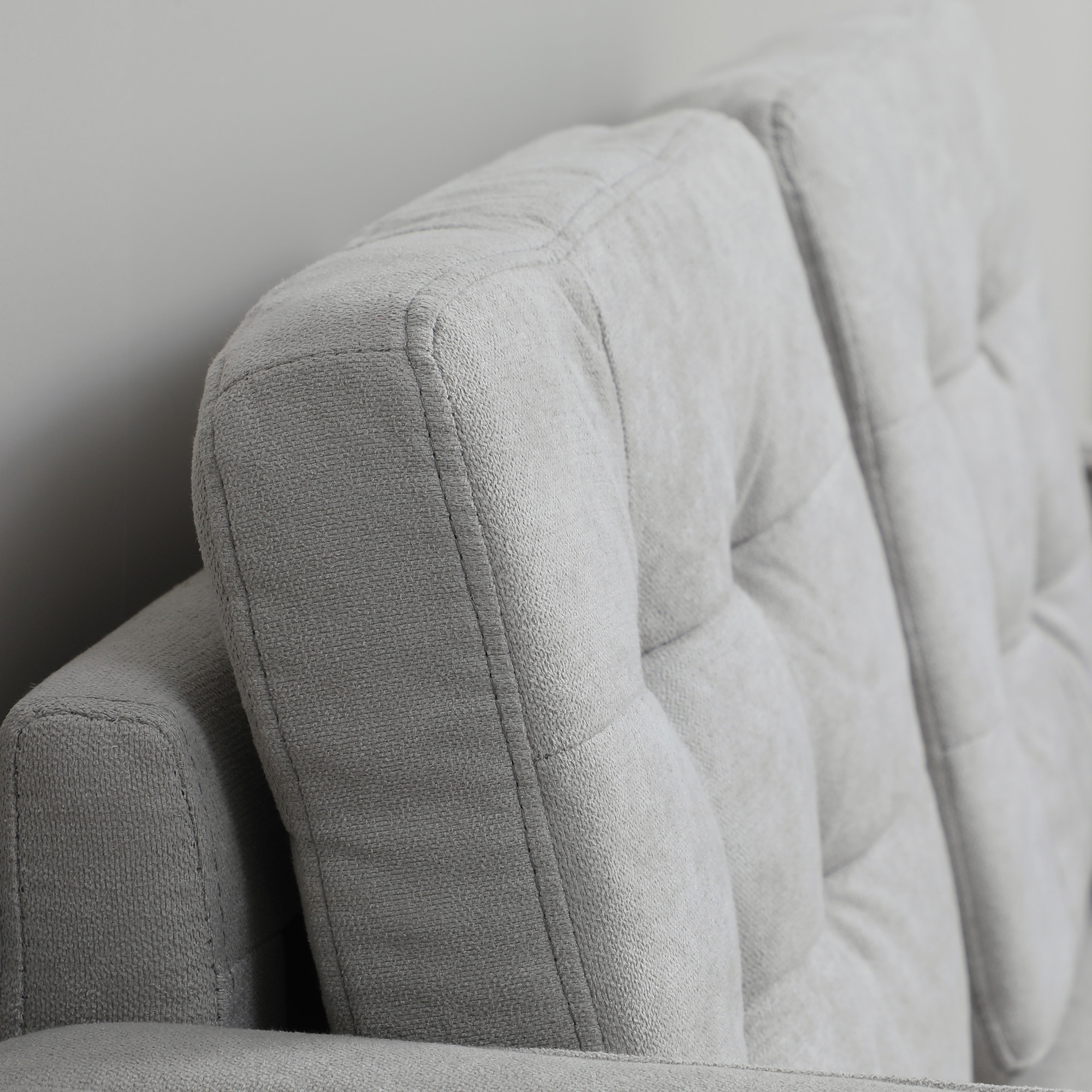 Nahaufnahme der Rückenlehne eines grauen Sofas. Mit getuftetem Design und sichtbaren Nähten.