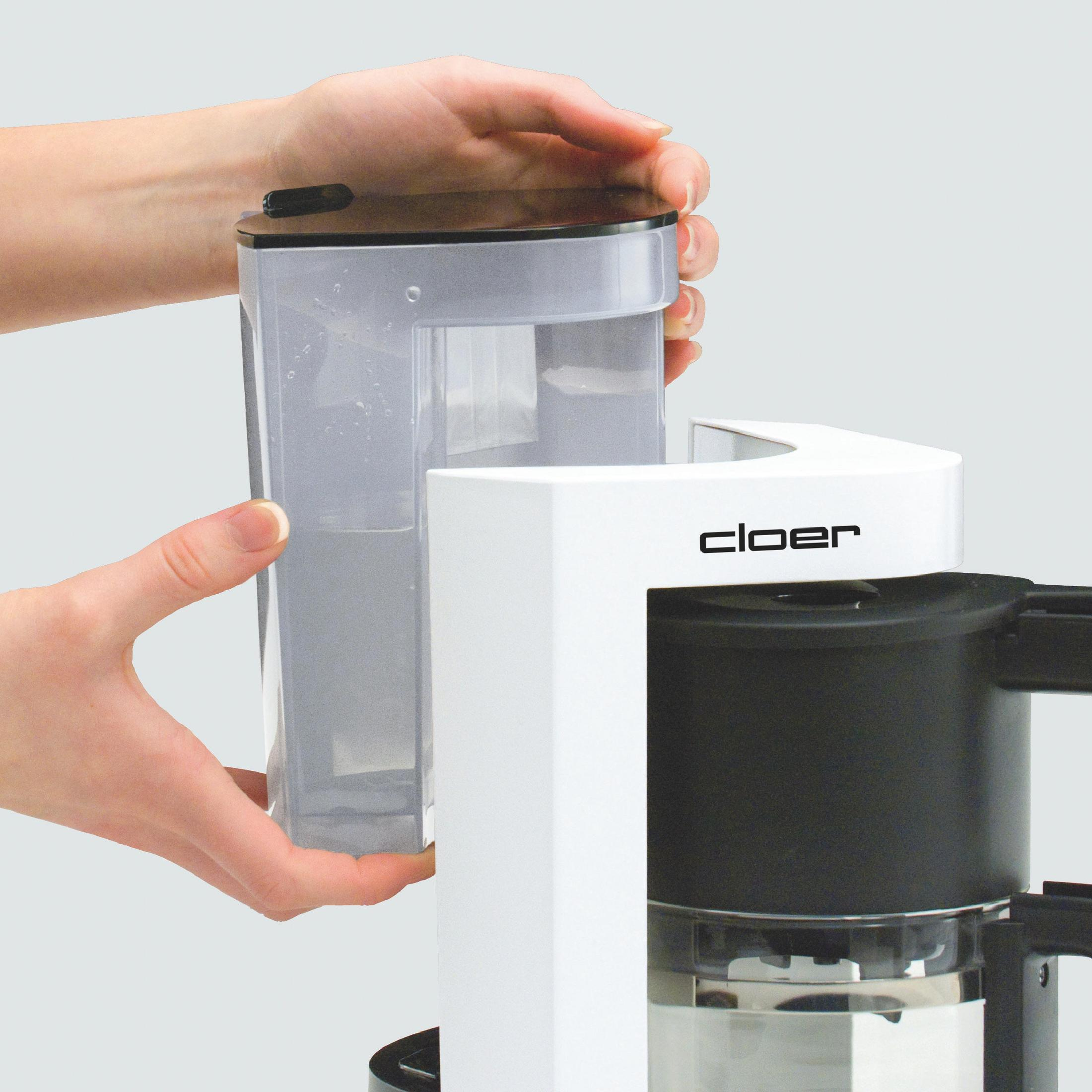 Mani che inseriscono un contenitore trasparente per l'acqua in una caffettiera bianca e nera. Cloer è scritto sopra.
