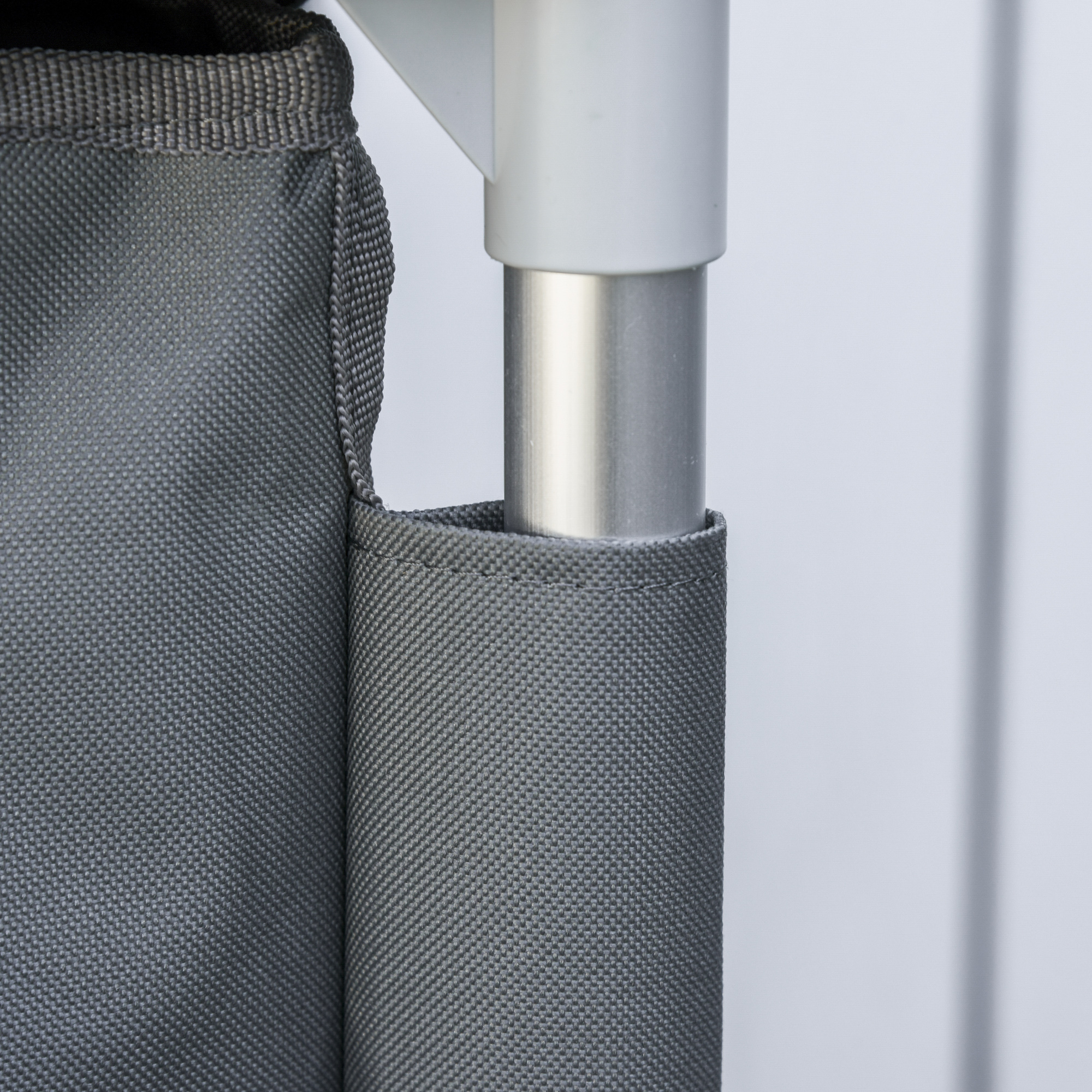 Nahaufnahme eines grauen Stoffpaneels auf einem weißen Rahmen, mit verstärktem Nahtdetail.