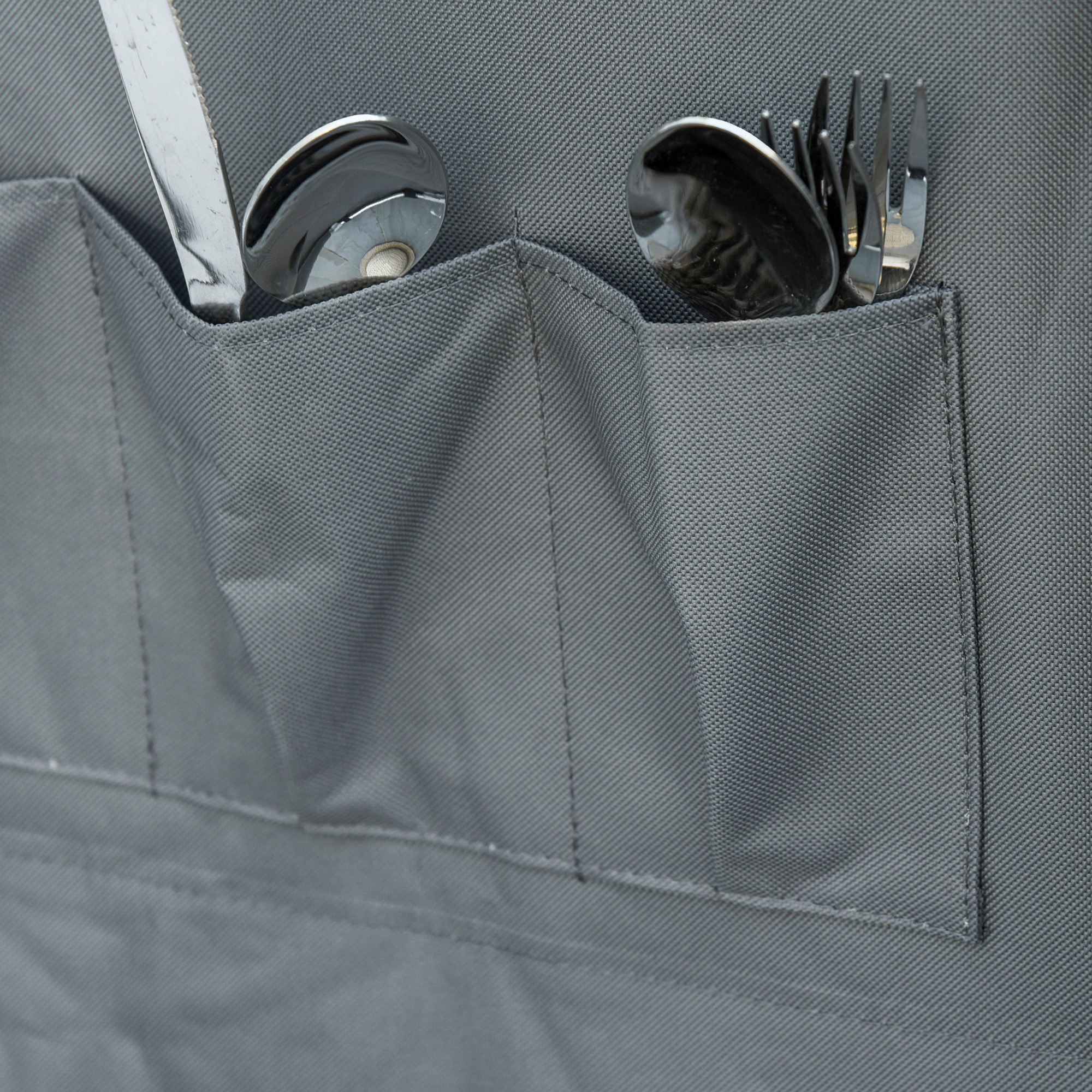 Nahaufnahme einer grauen Stofftasche mit Messer, Löffel und Gabel.