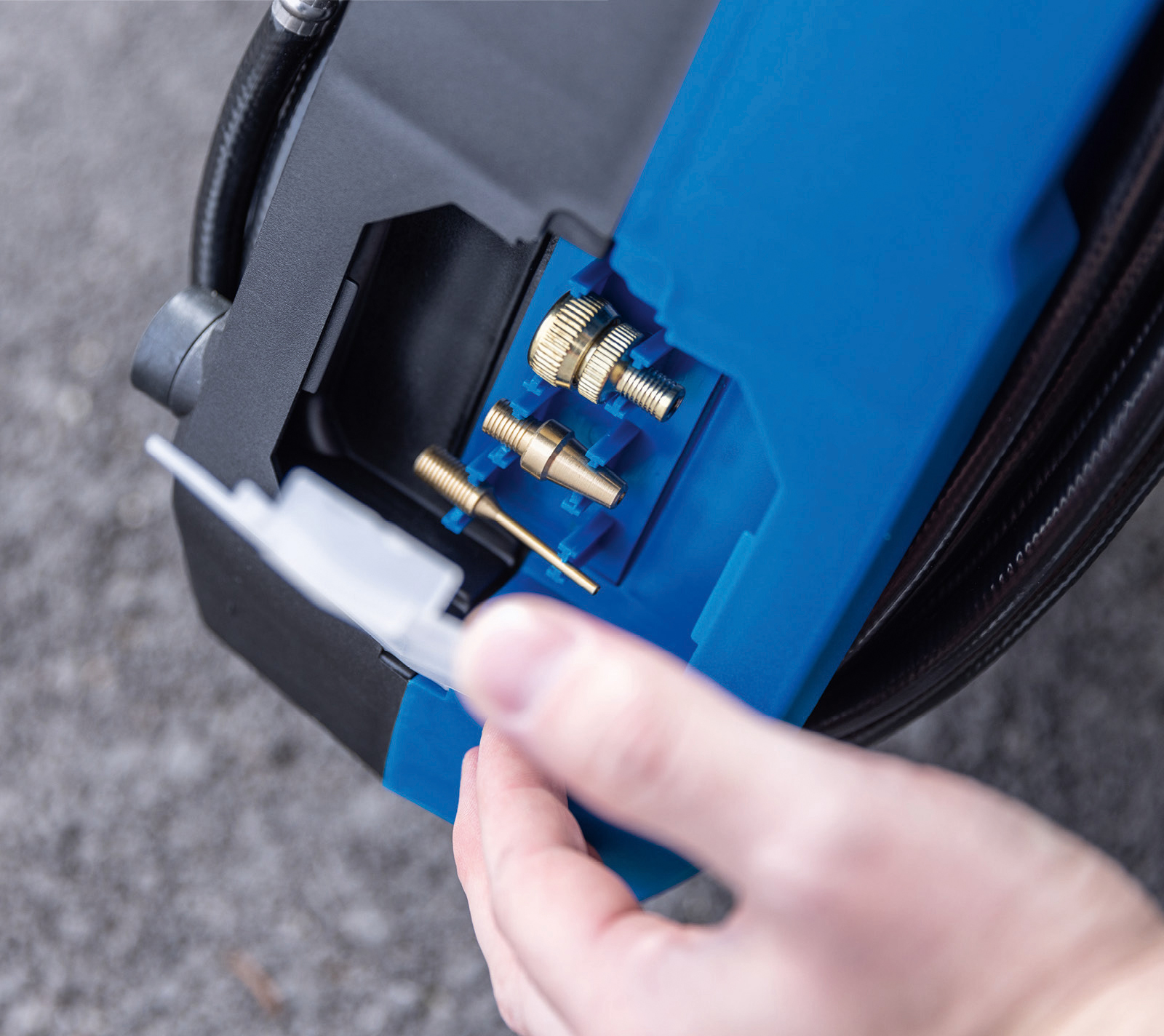 De hand van een persoon opent een blauw compartiment met diverse metalen connectoren.