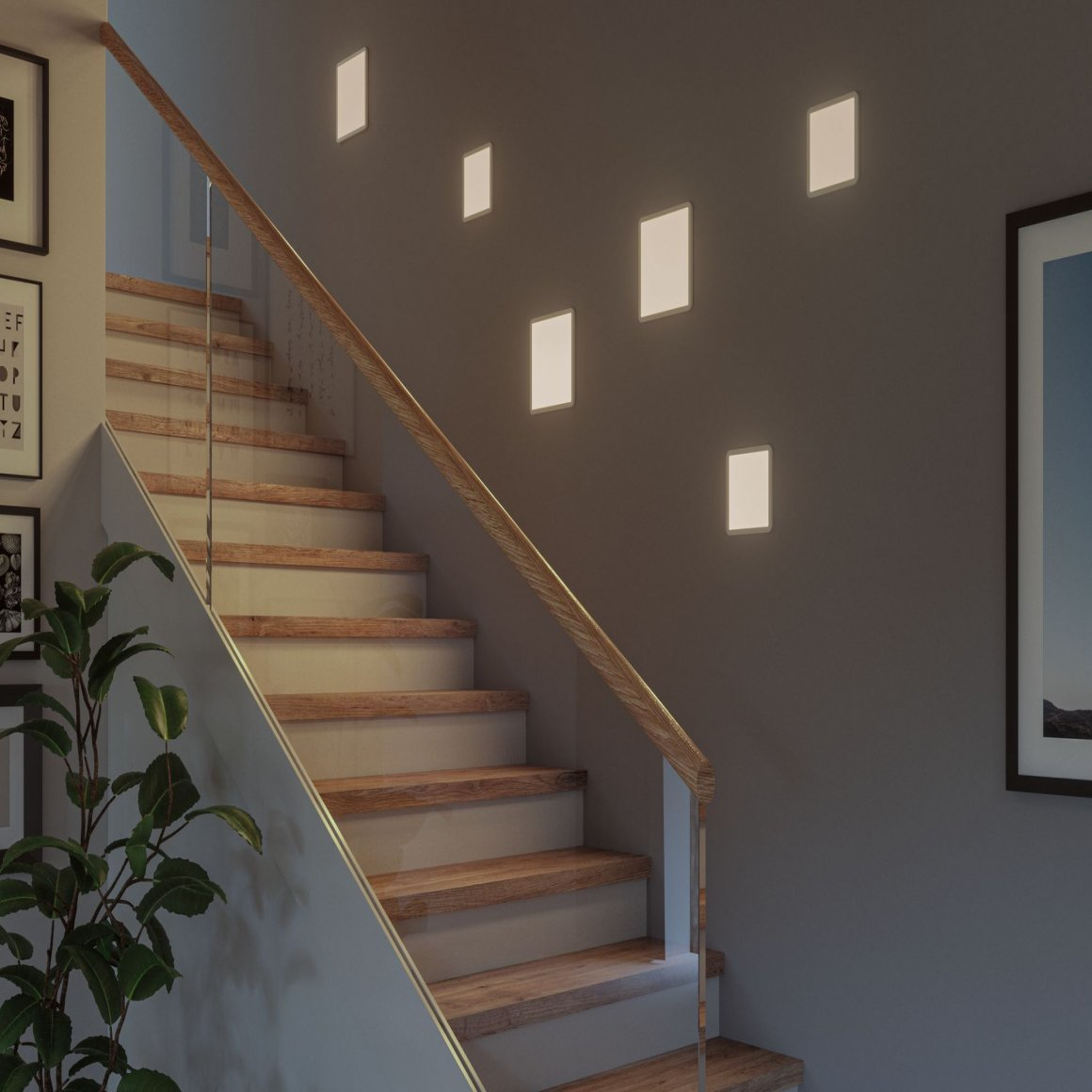 Treppe mit Holzstufen, Glasgeländer und rechteckigen Lichtern an einer grauen Wand. Pflanze links.