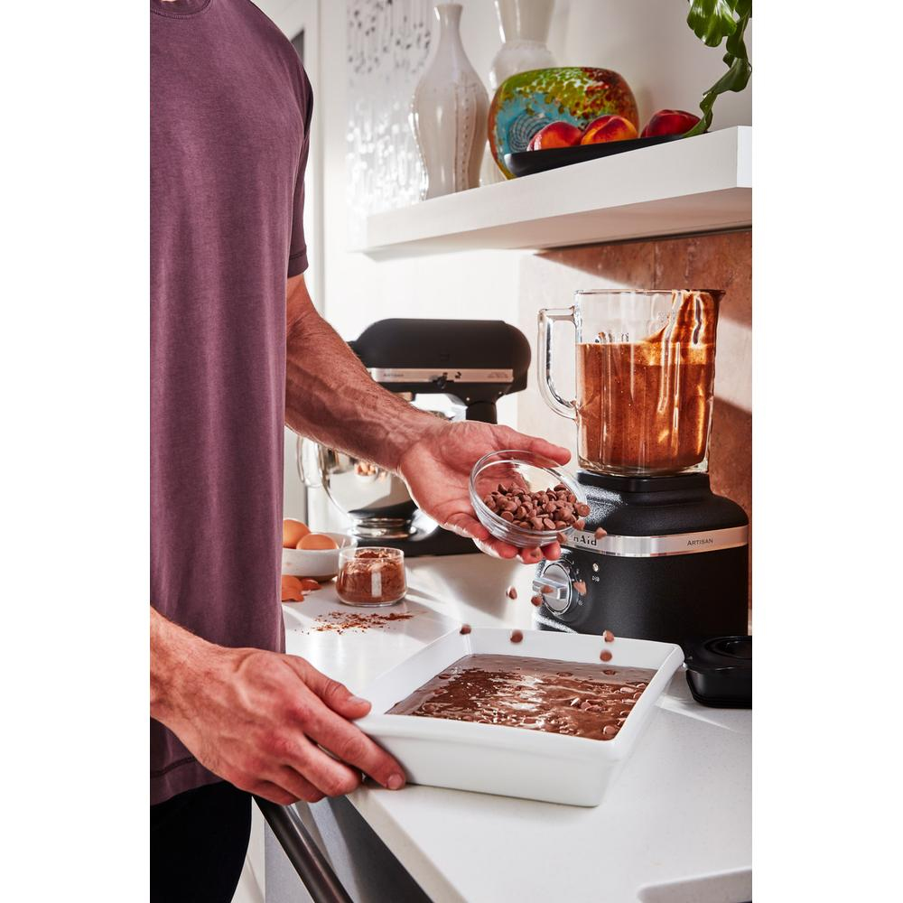 Eine Person gießt Schokoladenstückchen in einen Mixer und vermischt sie mit den Zutaten.