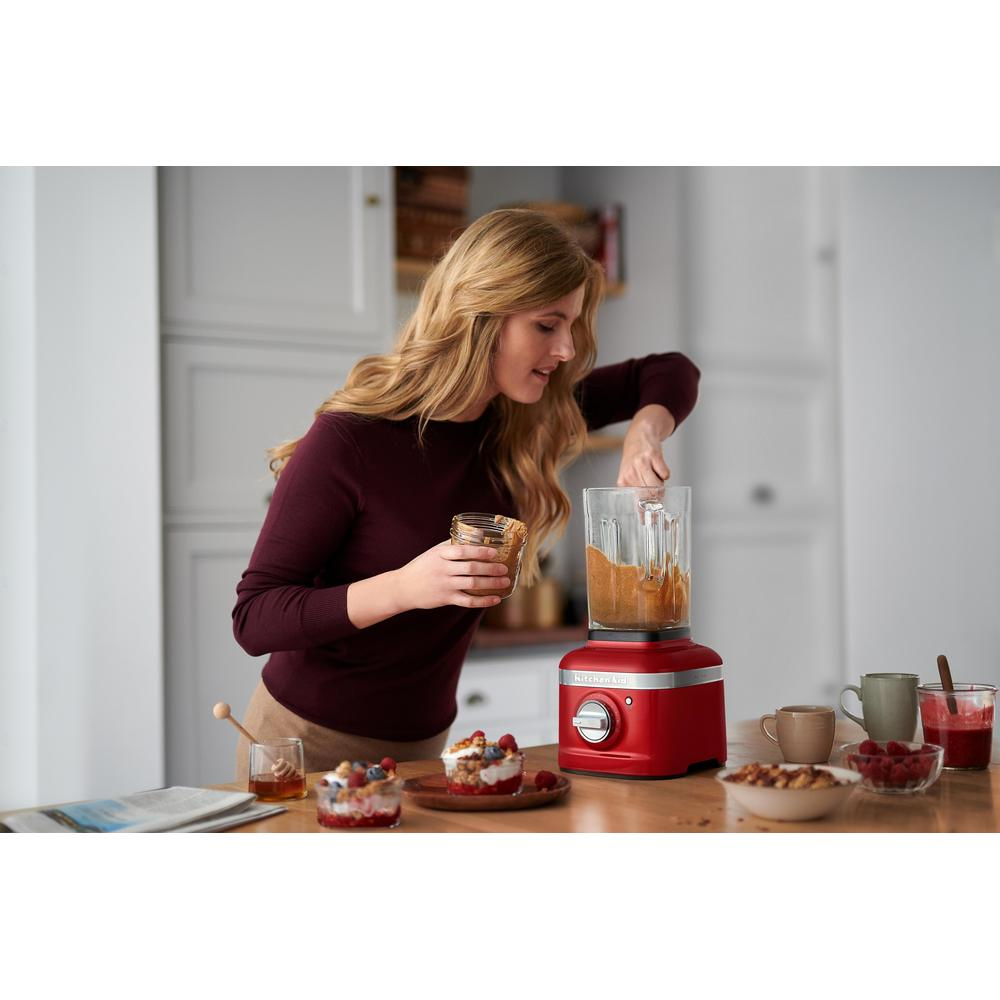 Kırmızı KitchenAid blender ile smoothie yapan, malzemeler ekleyen kadın.