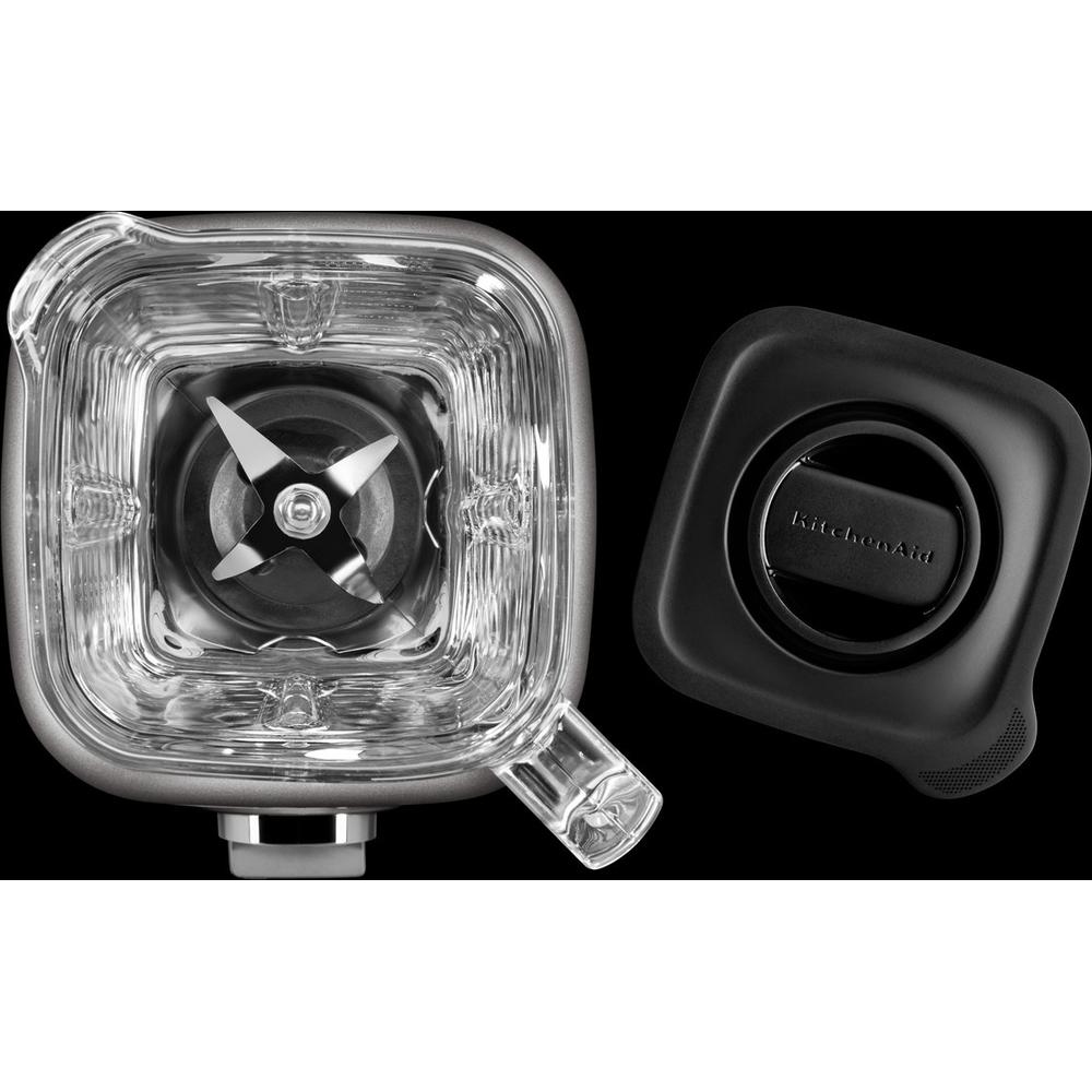 Zbliżenie podstawy i pokrywy blendera. Pokrywa jest czarna, z otworem. Podstawa pokazuje ostrza w środku.