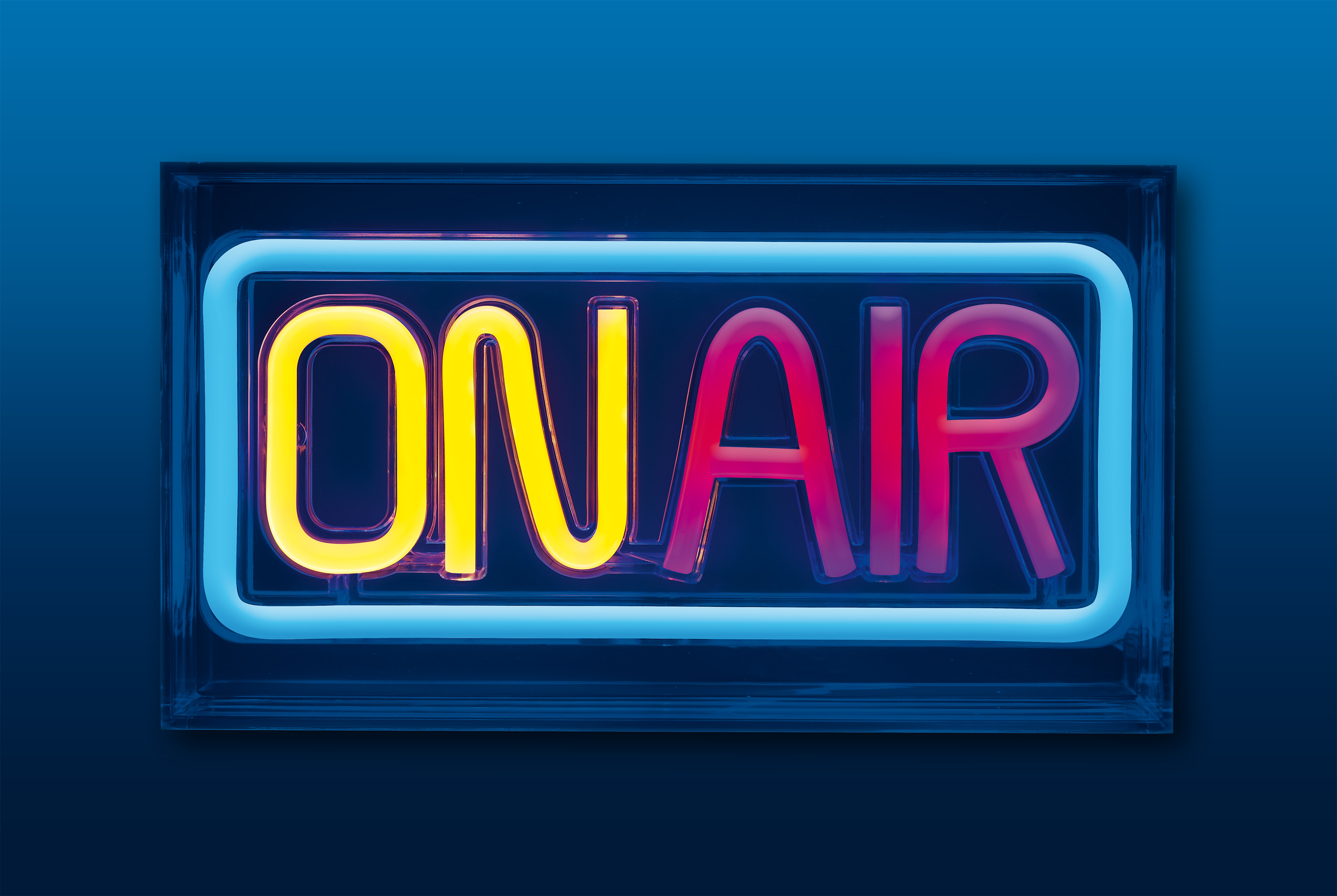 Neonowy znak z napisem 'ON AIR' z żółtymi i czerwonymi literami w niebieskiej ramce.