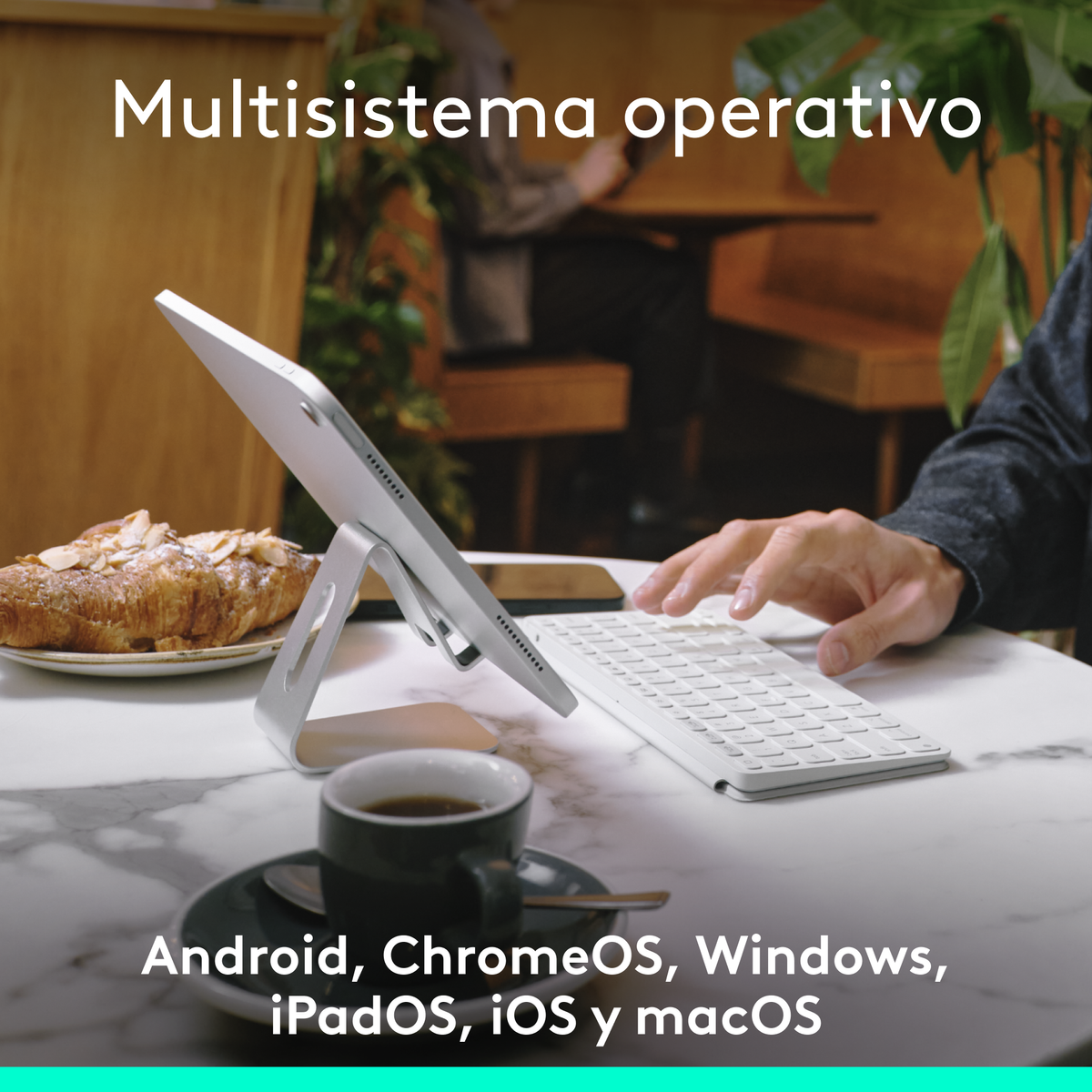 Un tablet su un supporto con tastiera. Un caffè e un pasticcino sul tavolo. Testo in spagnolo.