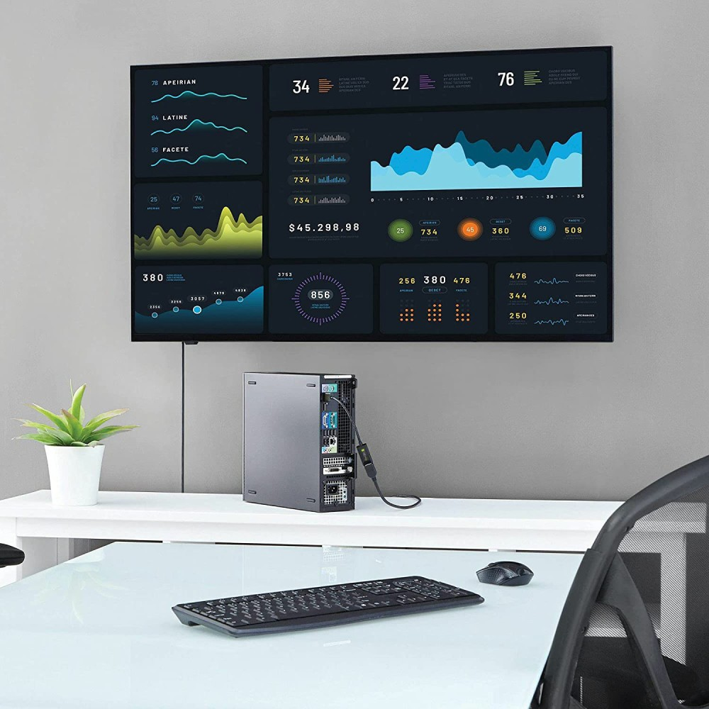 Un monitor que muestra gráficos y datos, con una computadora y un teclado debajo.