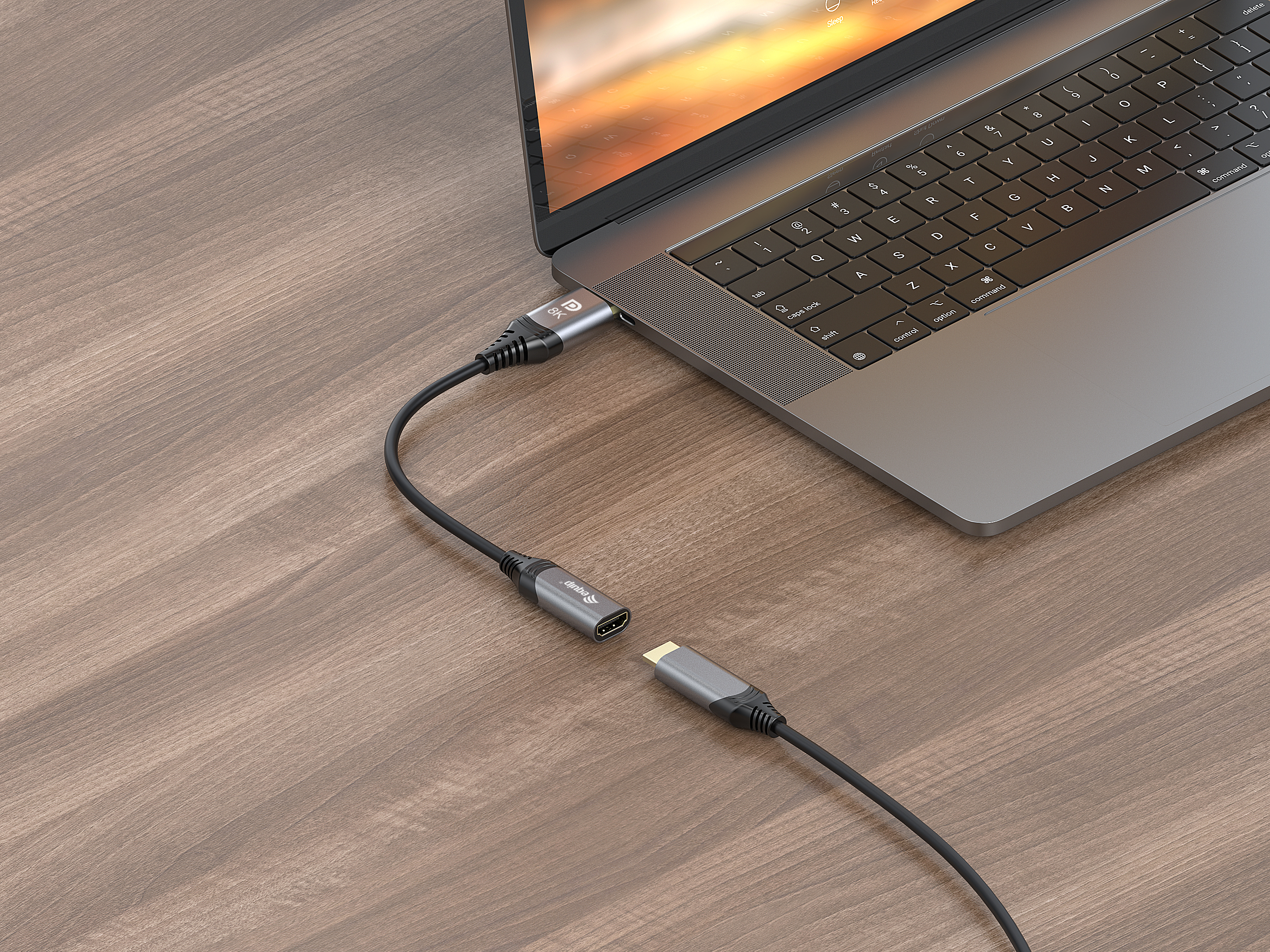 Ordenador portátil conectado a un adaptador negro mediante un cable sobre una mesa de madera.