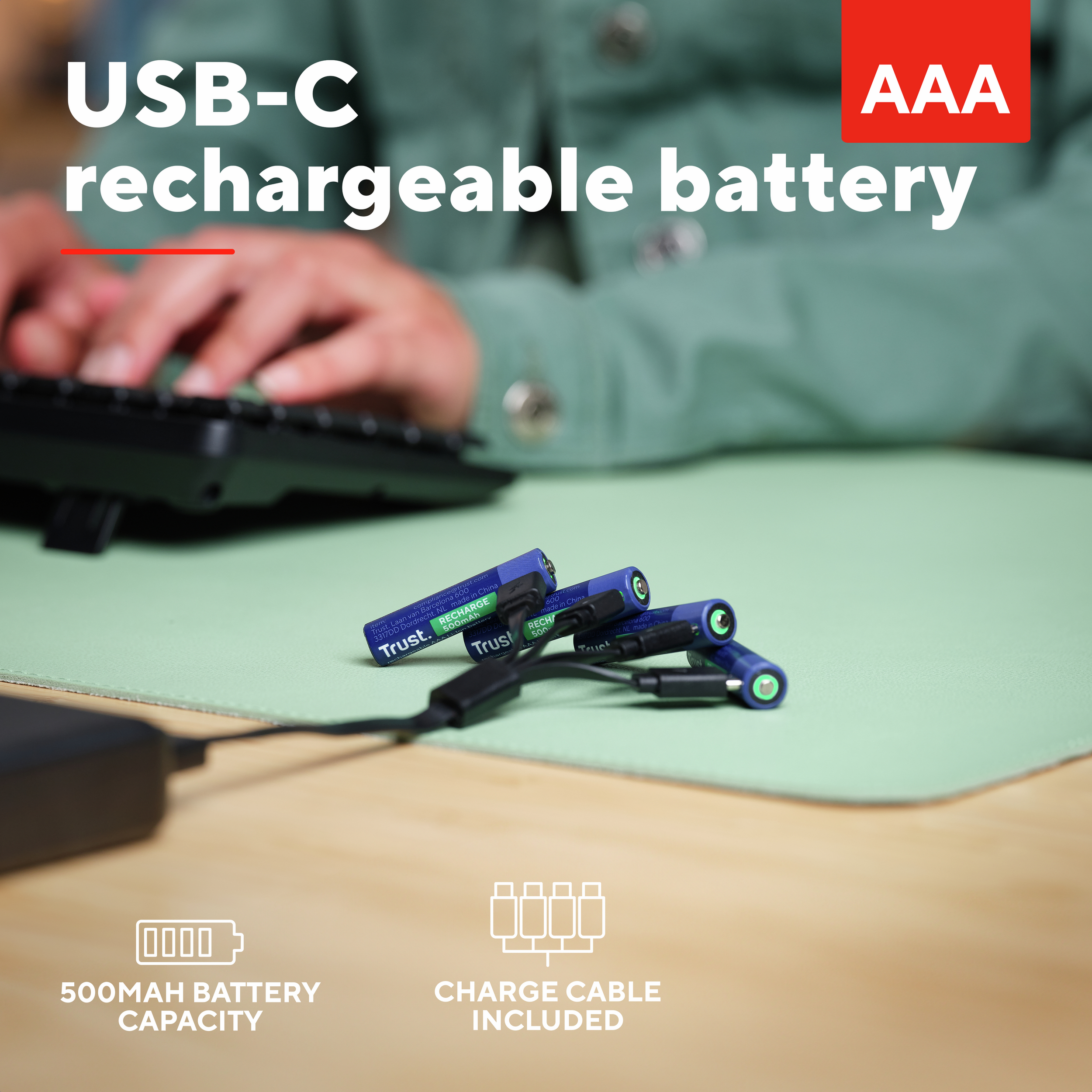 Kobieta pisze na klawiaturze. Na pierwszym planie akumulatory i kabel do ładowania.