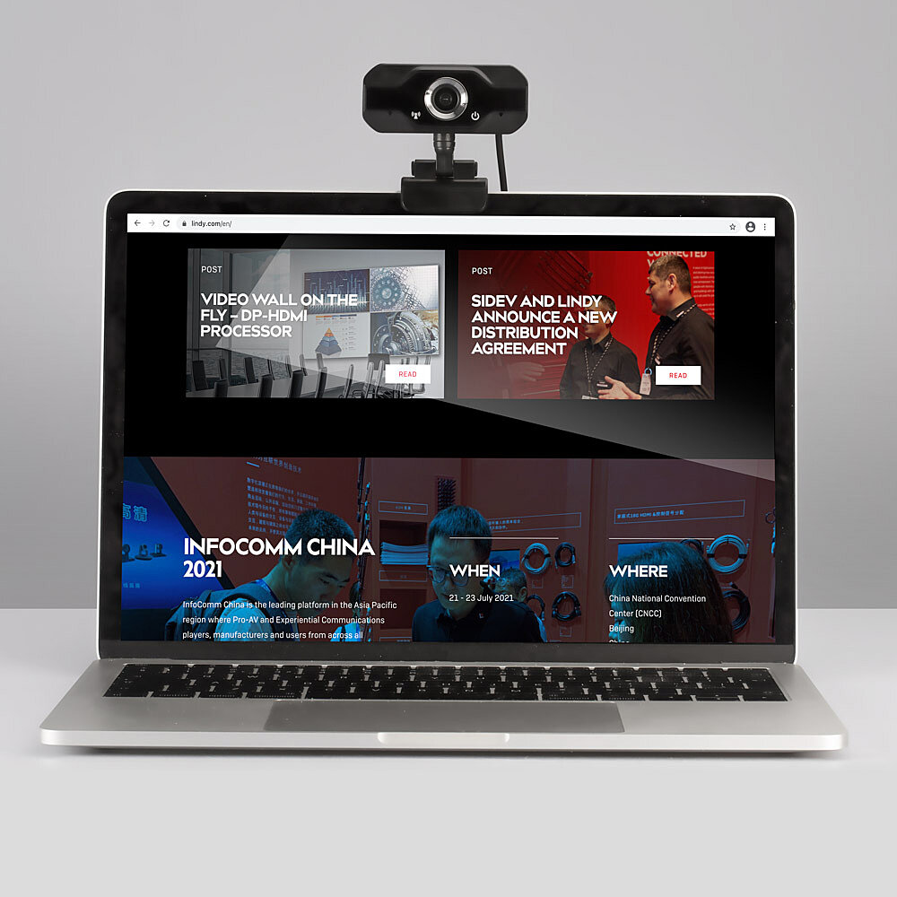 Un laptop con webcam sopra, mostra un sito web su un evento.