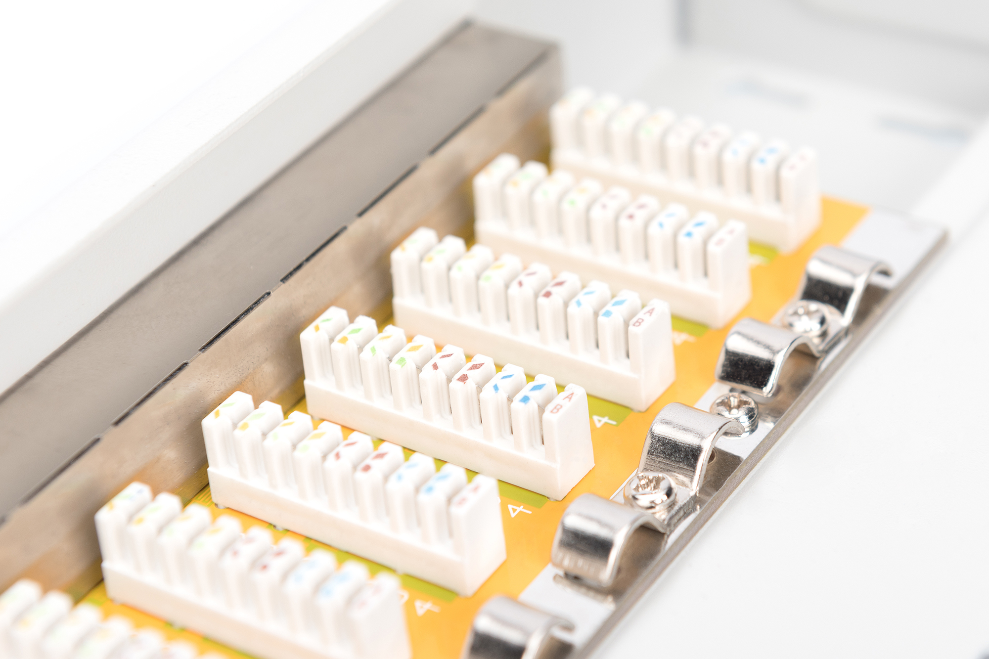 Primo piano di connettori modulari con pin colorati e clip metalliche, su superficie bianca.