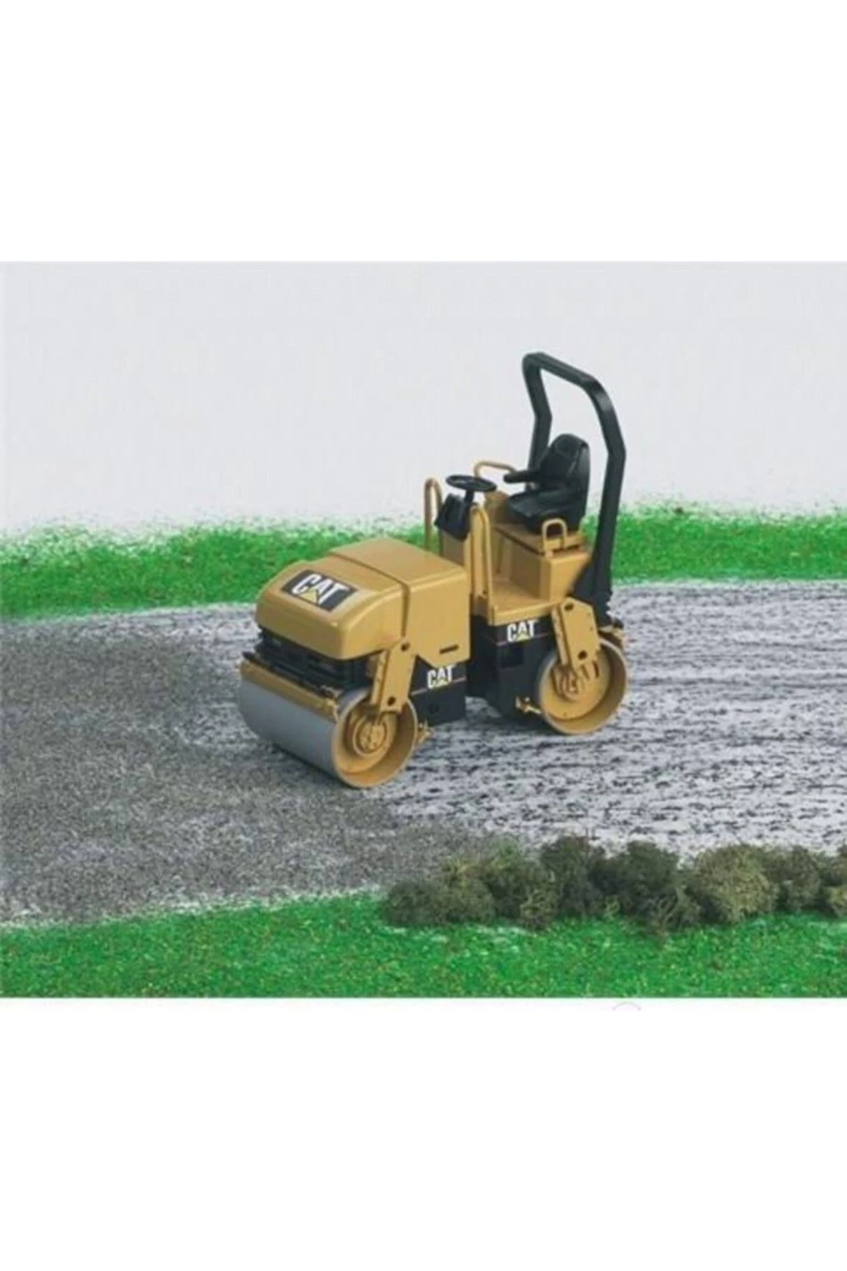 Żółta zagęszczarka CAT na drodze z zielonym tłem.