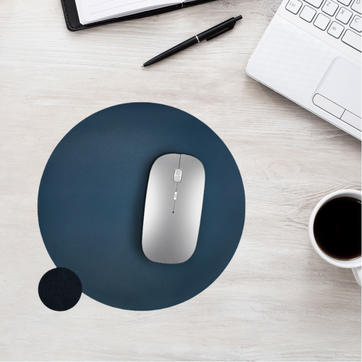 Un mouse wireless argentato su un tappetino blu scuro, su una scrivania di legno chiaro.