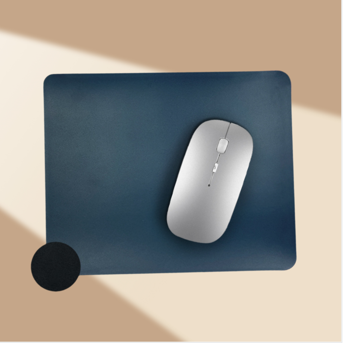 Un mouse argentato su un tappetino blu scuro, con un cerchio nero nell'angolo.