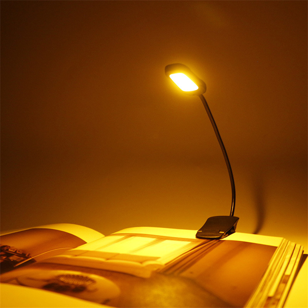 Eine flexible Lampe mit hellem Licht ist an einem Buch befestigt und beleuchtet die Seiten. Warmer Hintergrund.