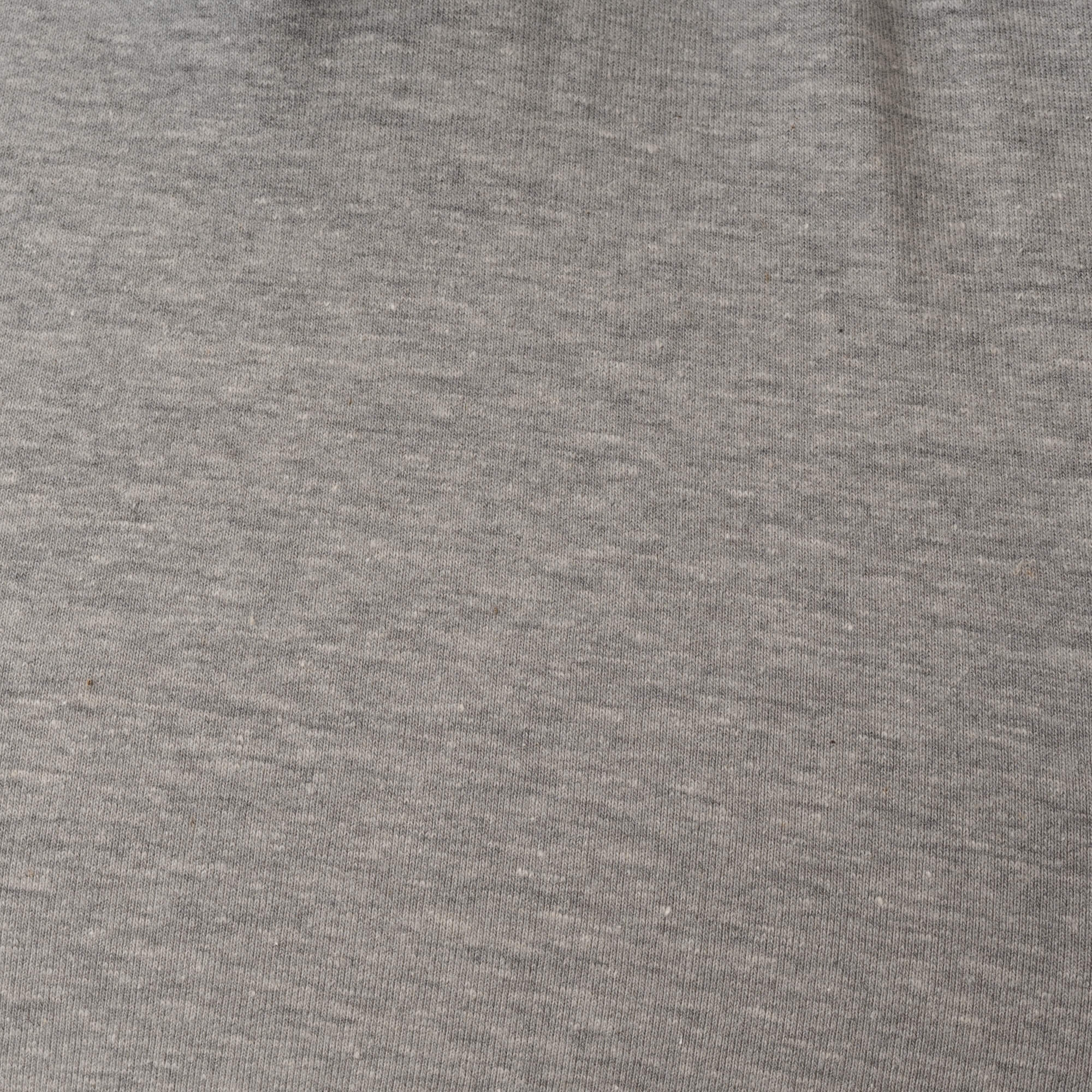 Primer plano de la textura de la tela gris, mostrando el patrón de tejido y sutiles variaciones de color.