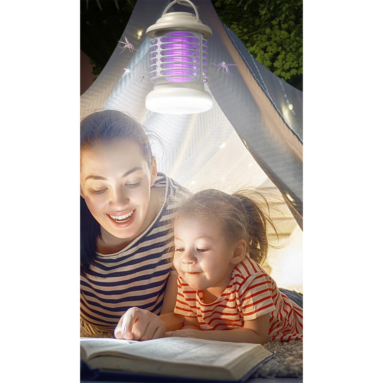 Mutter und Kind lesen ein Buch in einem Zelt, beleuchtet von einer Insektenvernichterlampe.