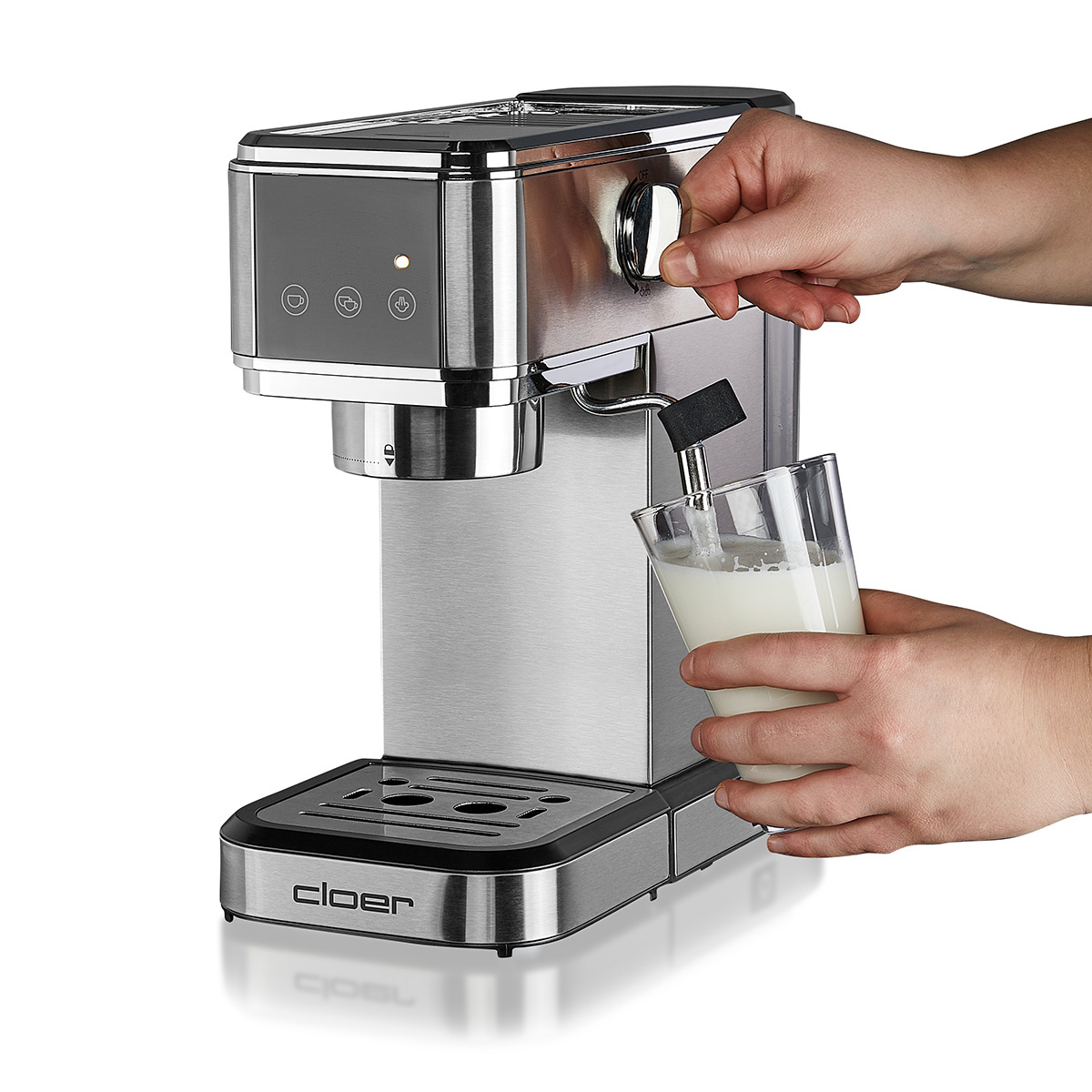 Eine Person gießt Milch in ein Glas mit einer silbernen und schwarzen Espressomaschine.