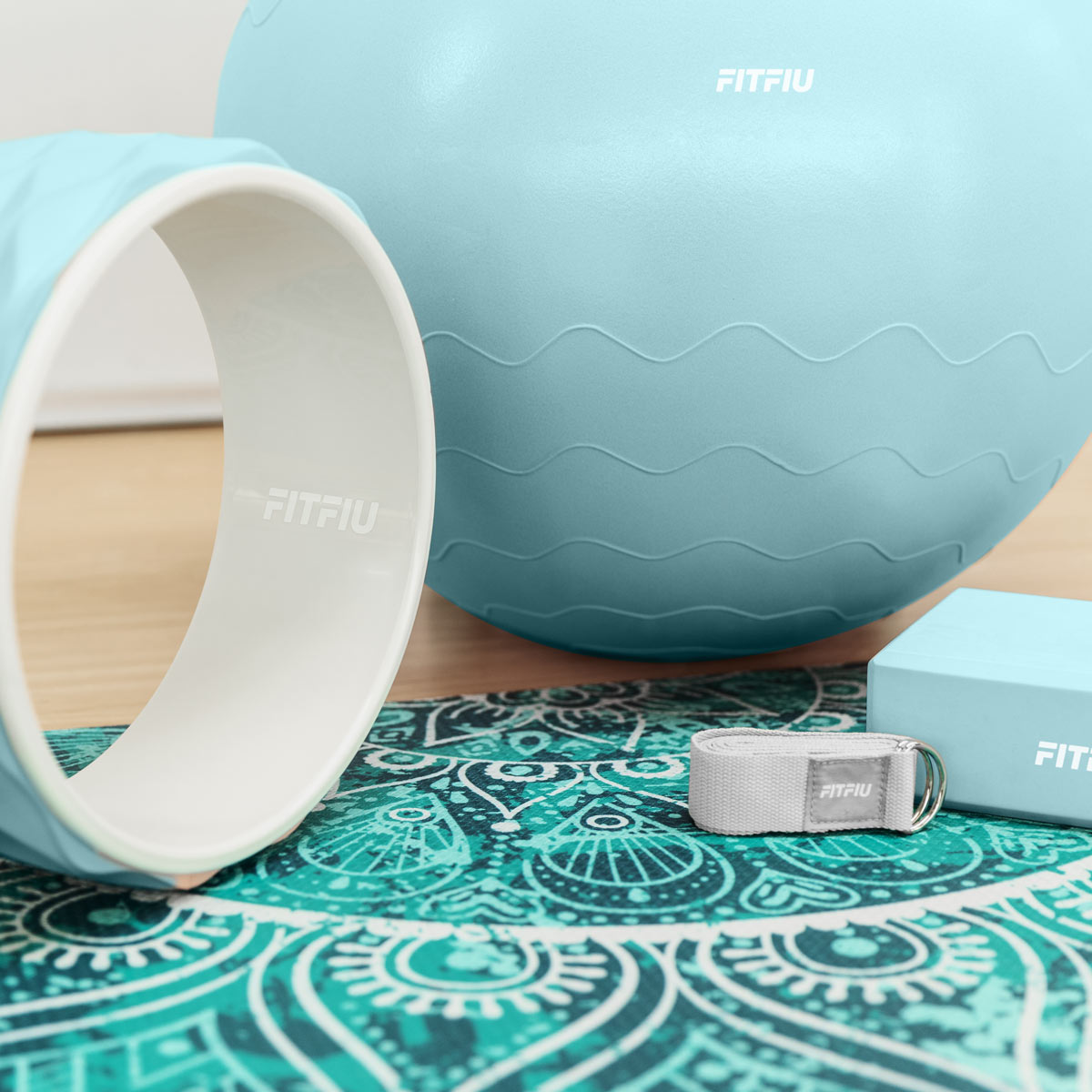 Equipo de yoga: anillo, pelota, bloque y banda. Todo es azul claro o gris. Esterilla turquesa con diseño mandala.
