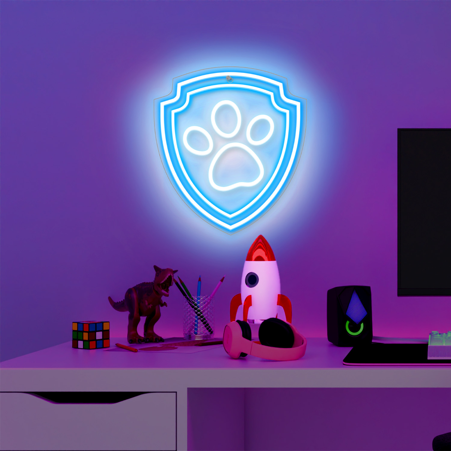 Neonowe światło tarczy Paw Patrol na ścianie z zabawkami na biurku.