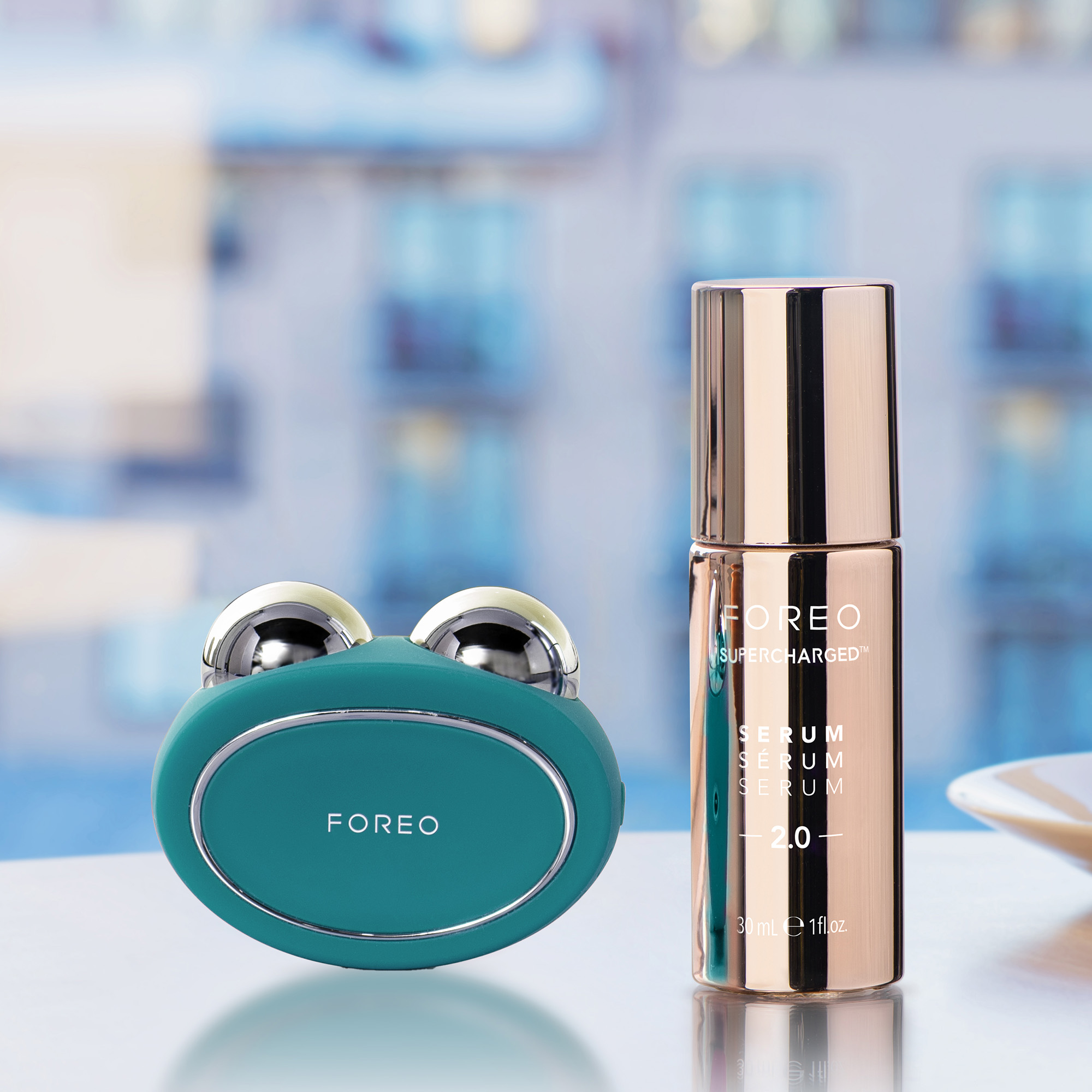 Facial device and serum bottle on a table, with a blurry background of a window.