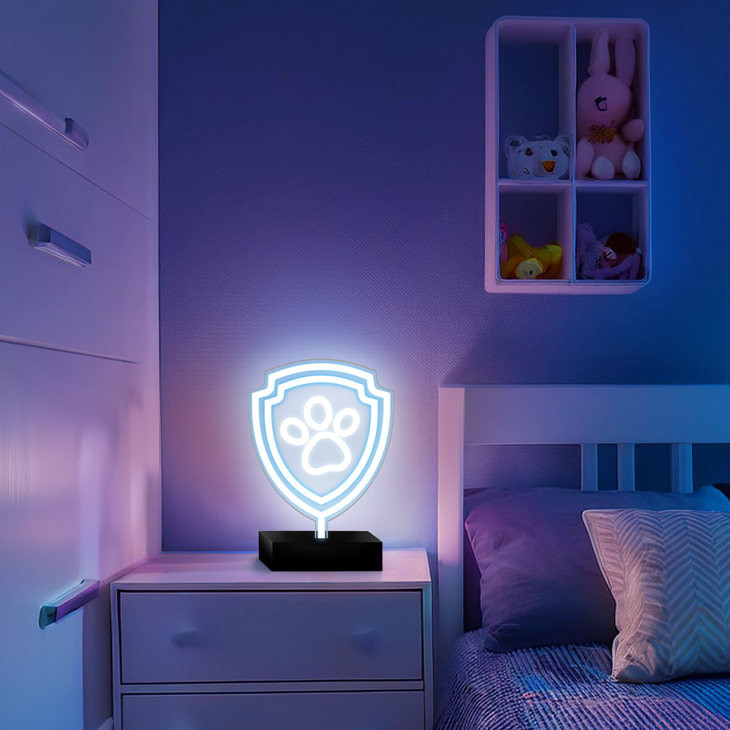 Neonowy znak Paw Patrol na stoliku nocnym, z łóżkiem w tle i pluszakami na półce.
