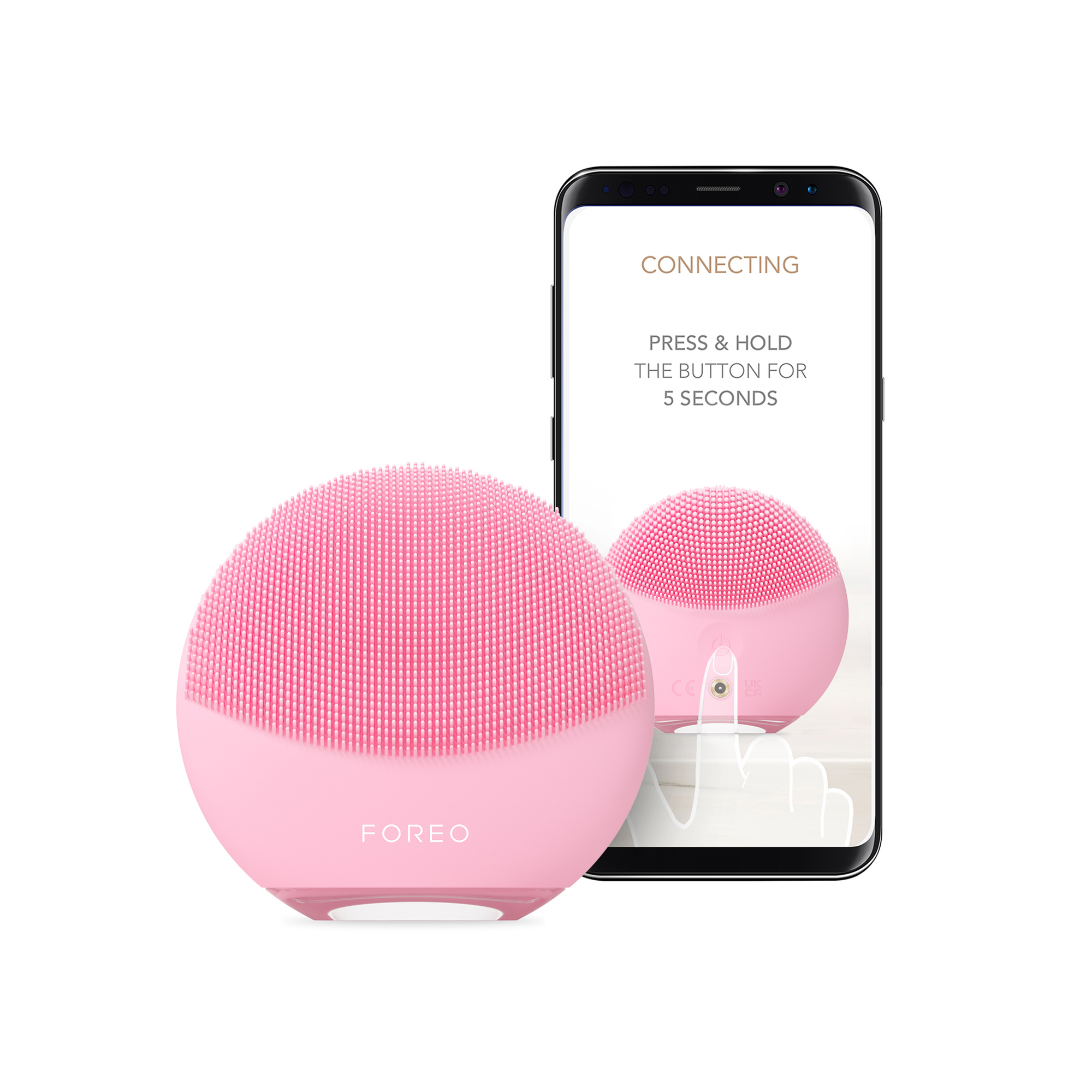 Pembe yüz temizleme cihazı, talimatların gösterildiği bir telefon ekranının yanında.