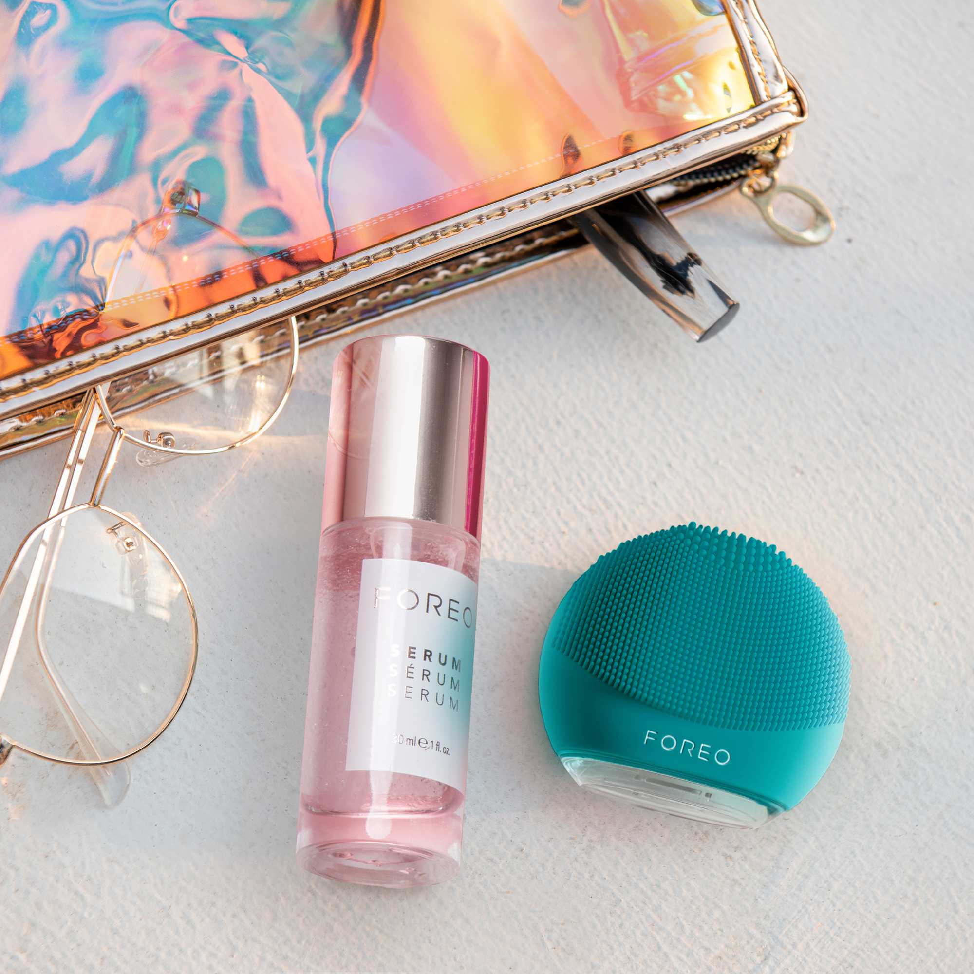 Skincare products and glasses on a white surface. Clear purse.