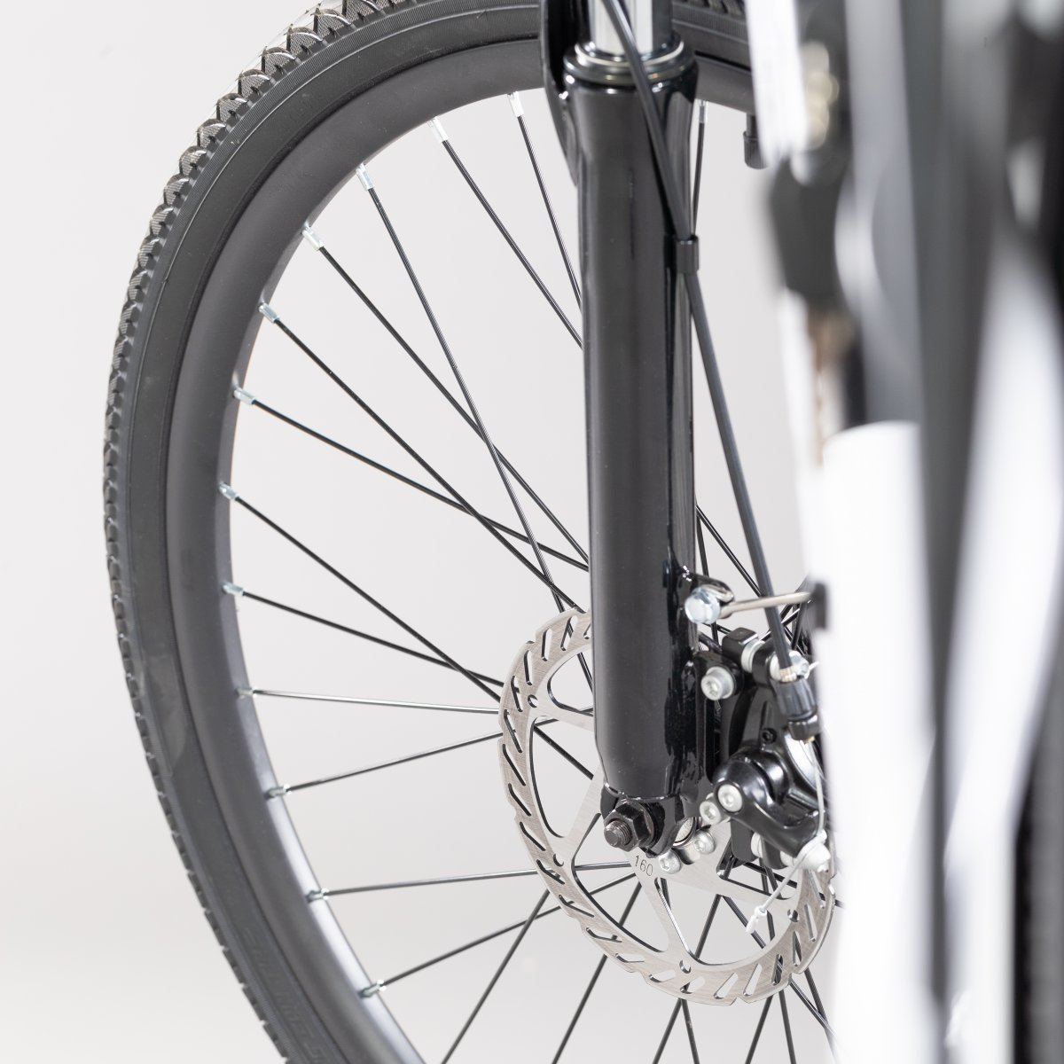 Zbliżenie koła roweru z systemem hamulców tarczowych i czarnym widelcem.