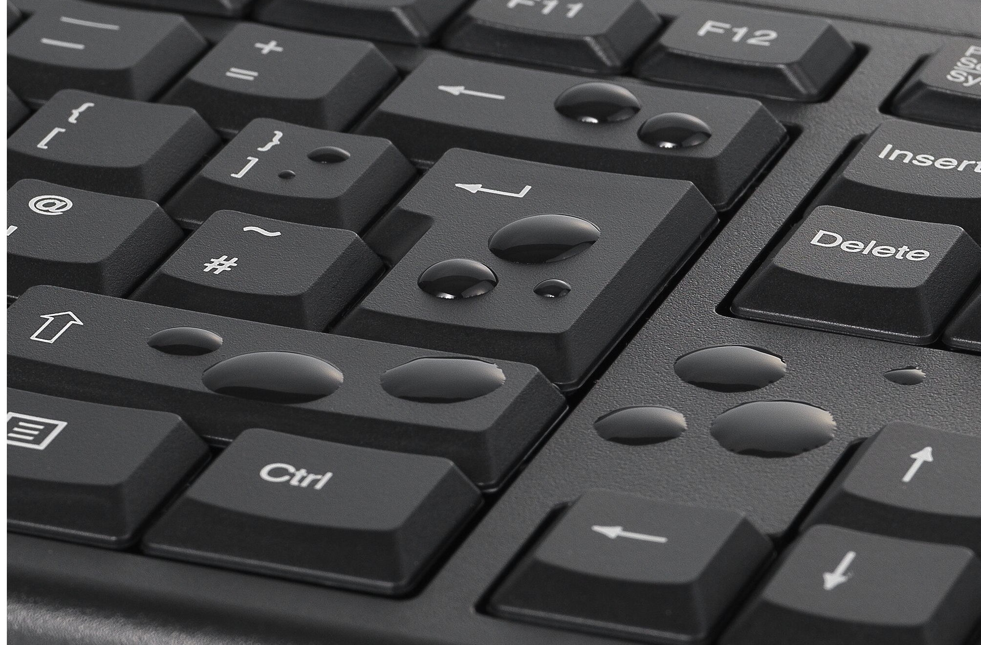 Zbliżenie czarnej klawiatury z kroplami wody na klawiszach.