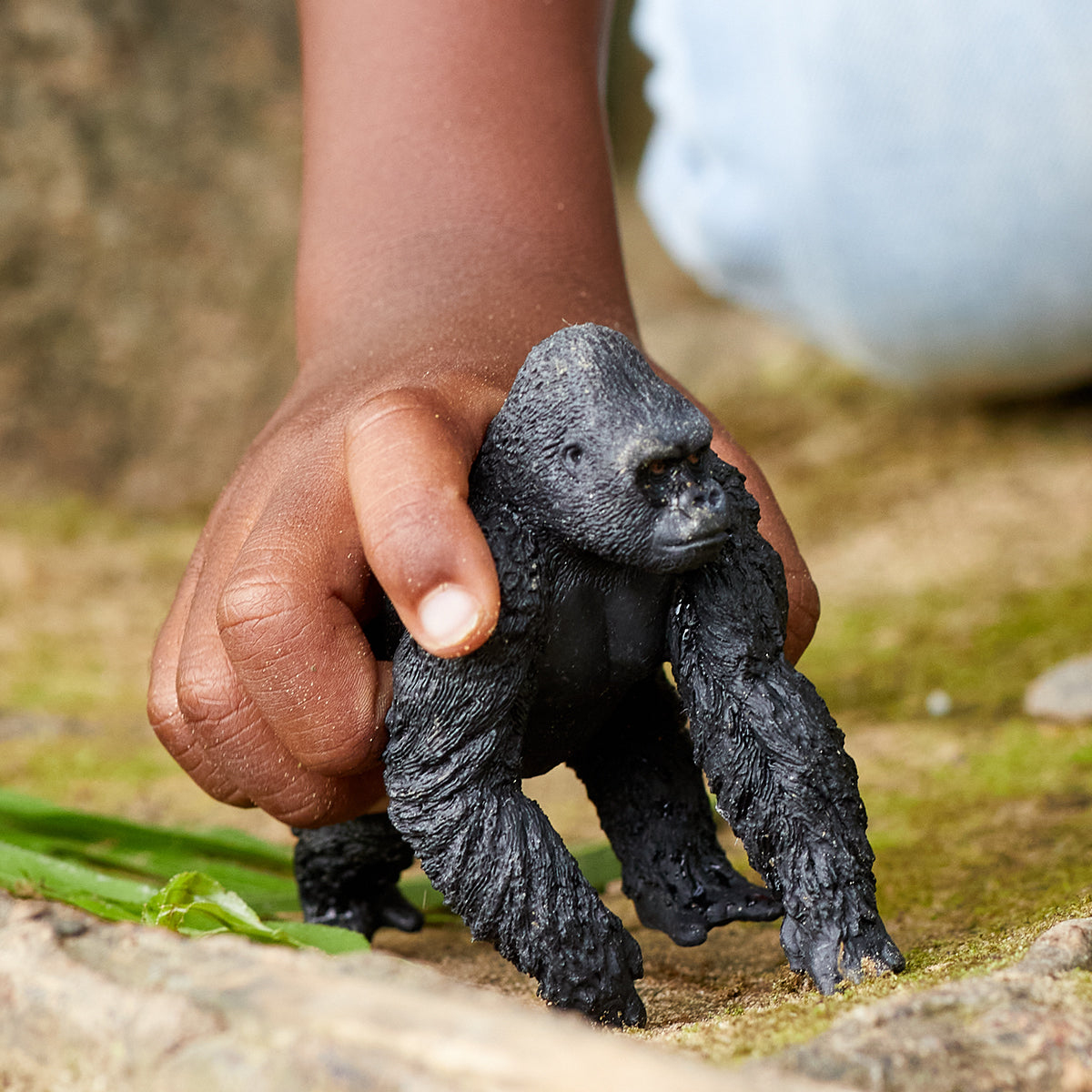 Primo piano della mano di un bambino che tiene un gorilla giocattolo nero.