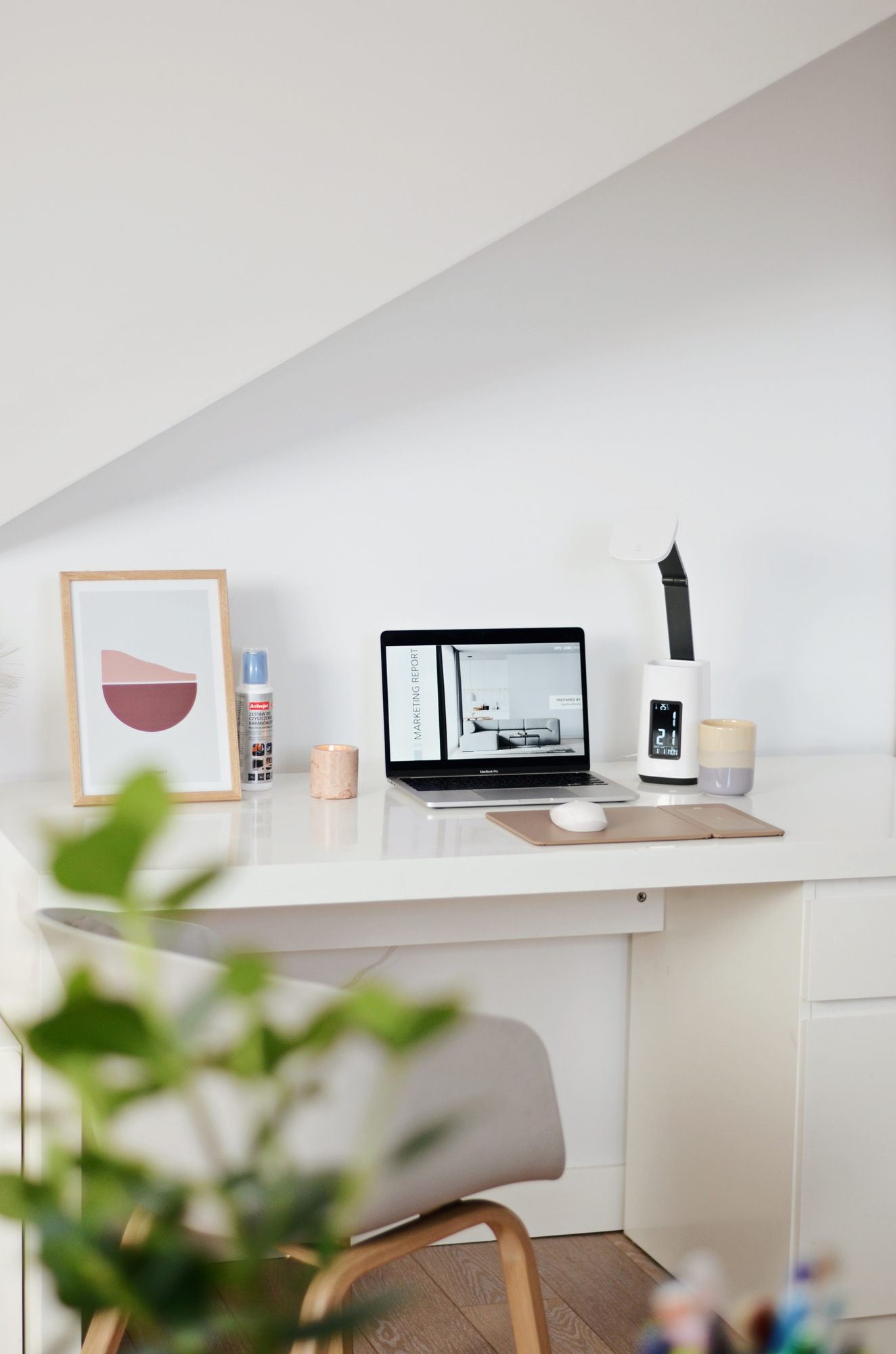 Biurko z laptopem, lampą i dekoracjami. Roślina i inne przedmioty są na biurku.
