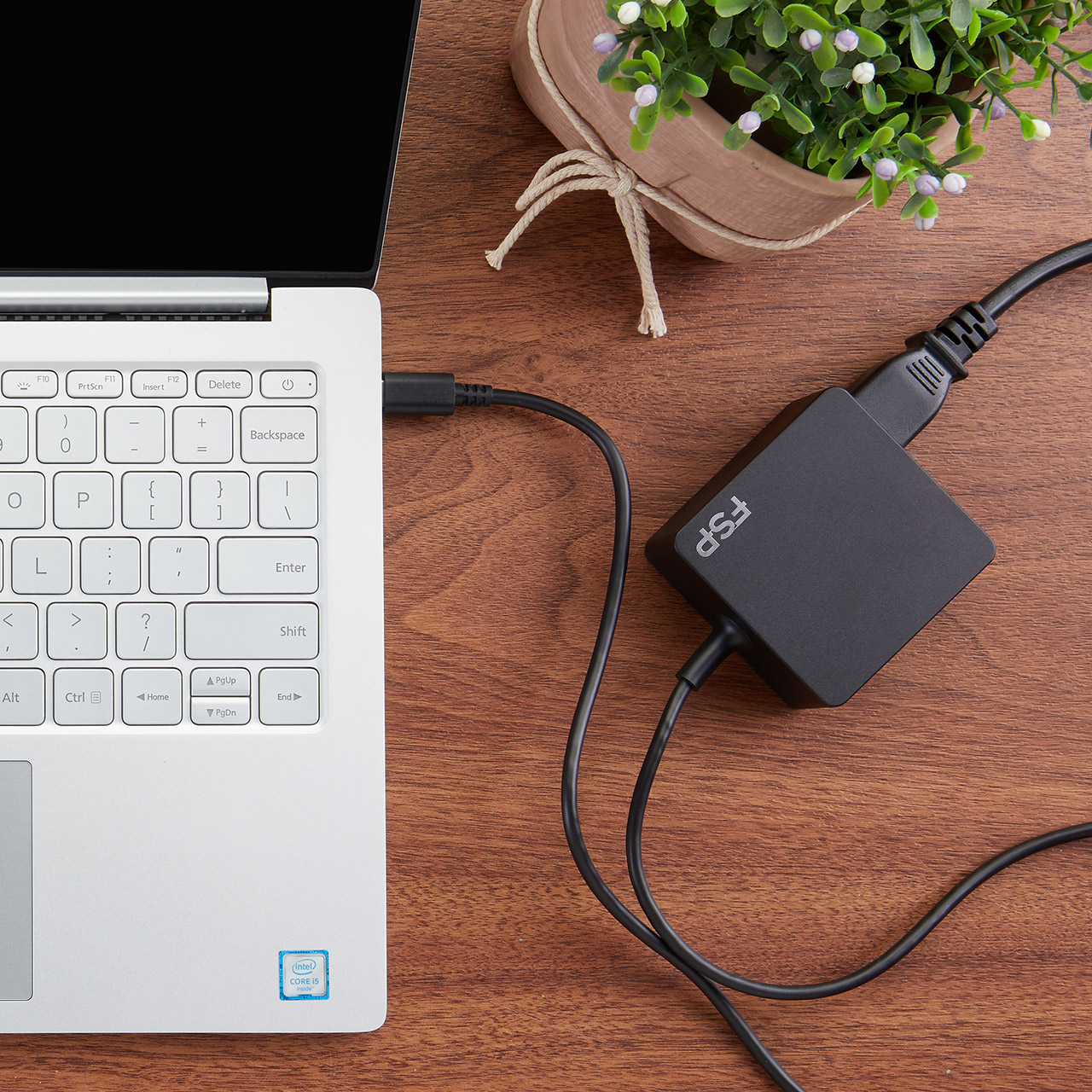 Ein weißer Laptop mit einem schwarzen Adapter, der an den USB-Anschluss angeschlossen ist.